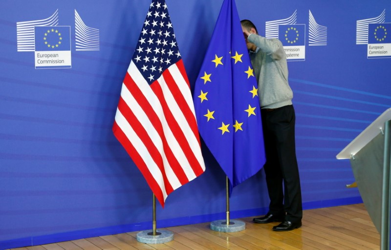 Un trabajador ajusta las banderas de Estados Unidos y la Unión Europea 