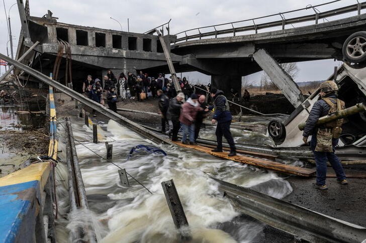 Decenas de personas cruzan un puente destruido sobre un río para abandonar la localidad de Irpín, cerca de Kiev, Ucrania