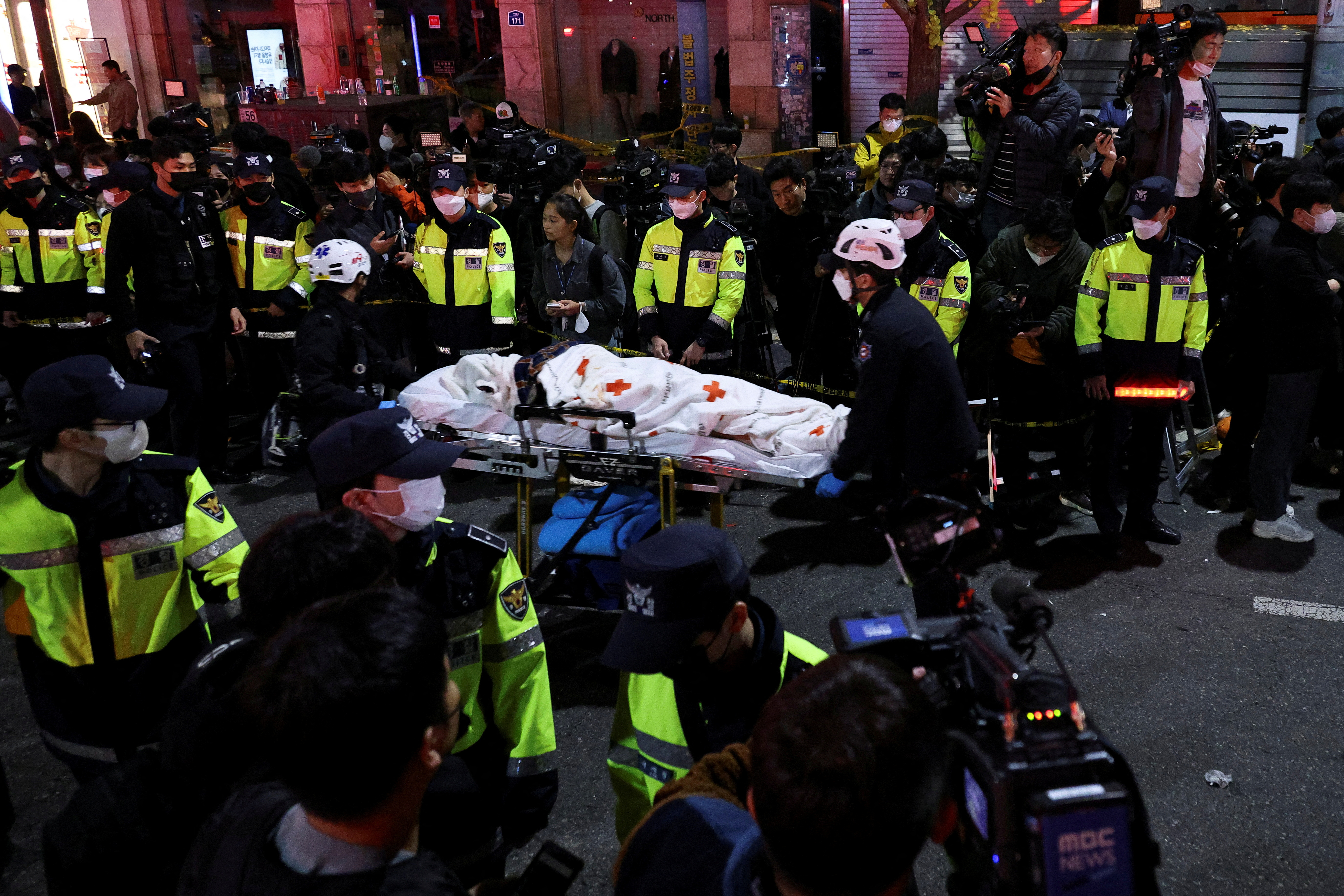 Los miembros del equipo de rescate mueven un cuerpo en la escena donde decenas de personas resultaron heridas en una estampida durante un festival de Halloween en Seúl, Corea del Sur, el 30 de octubre de 2022 (Reuters)