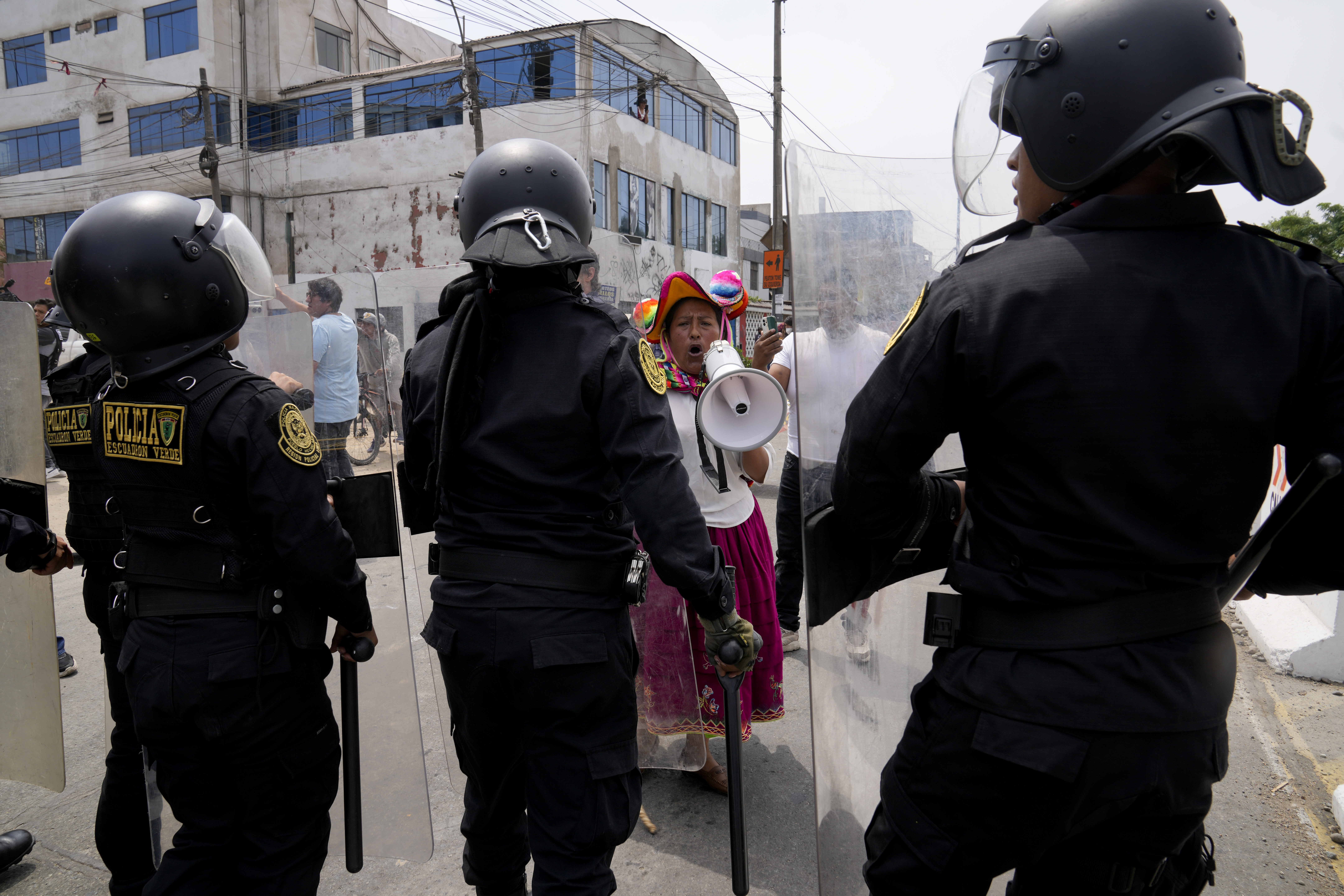 An anti-government protester challenges police surrounding the San Marcos University in Lima, Peru, Saturday, Jan. 21, 2023. Police evicted from the university grounds protesters who arrived from Andean regions seeking the resignation of President Dina Boluarte, the release from prison of ousted President Pedro Castillo and immediate elections. (AP Photo/Martin Mejia)