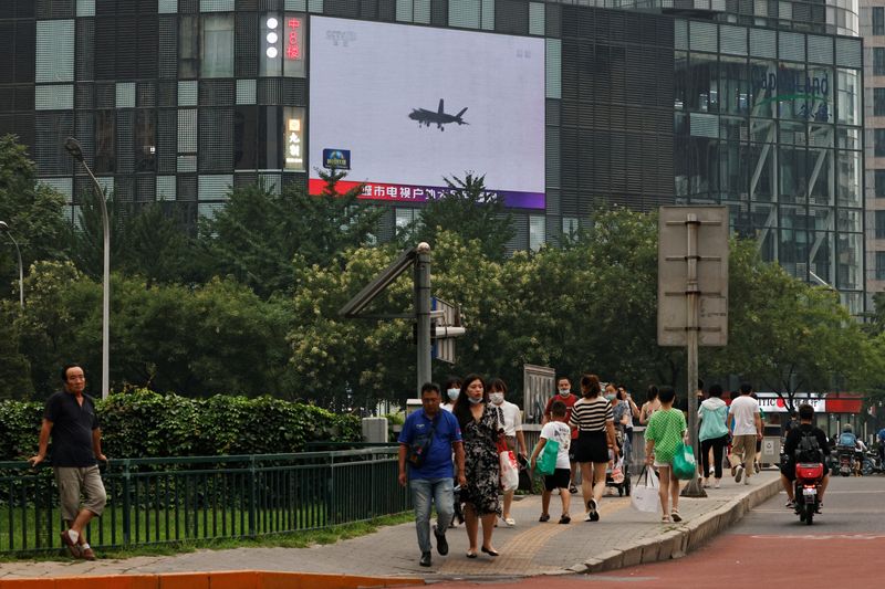 FOTO DE ARCHIVO. Los peatones pasan por delante de una pantalla gigante que emite un informe de noticias sobre los ejercicios militares del Ejército Popular de Liberación (EPL) chino en torno a Taiwán, en Pekín, China. 4 de agosto de 2022. REUTERS/Thomas Peter