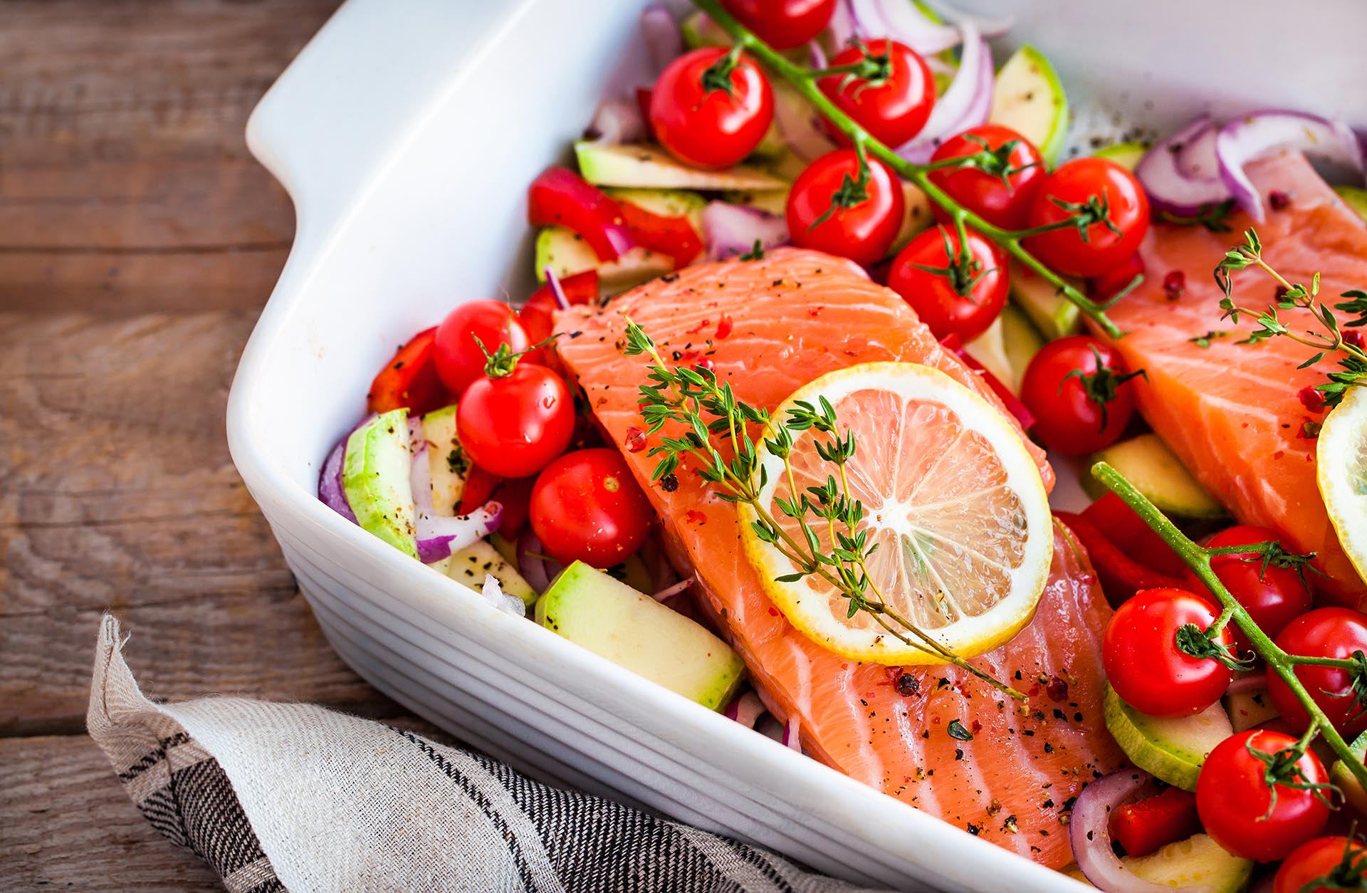 Raw fresh delicious salmon, cherry tomatoes, onion, zucchini, pepper and lemon in pan, ready to cook