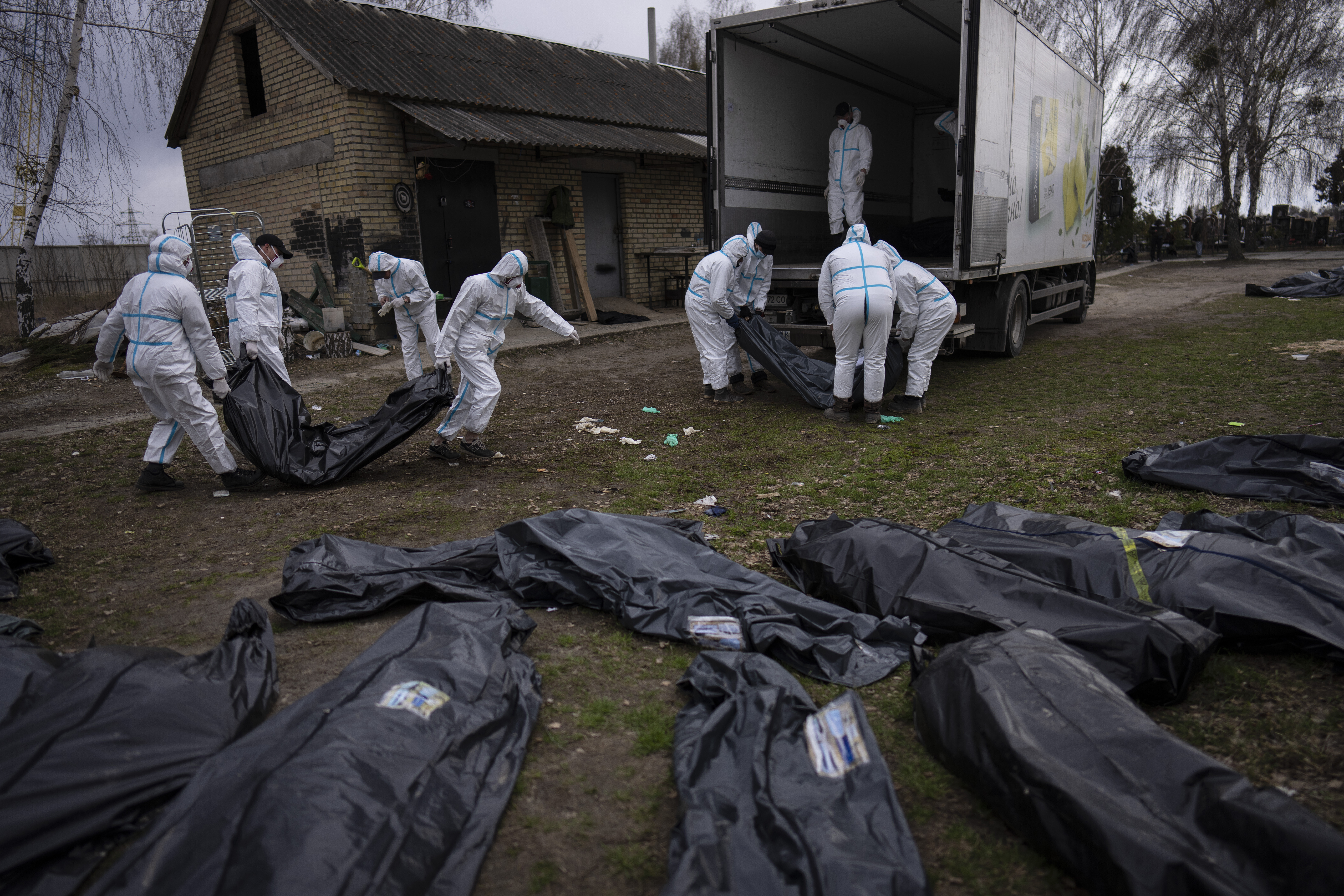 ARCHIVO - Voluntarios cargan cuerpos de civiles asesinados en Bucha en un camión para ser llevados a una morgue para su investigación, en las afueras de Kyiv, Ucrania, el martes 12 de abril de 2022. (Foto AP/Rodrigo Abd, Archivo)

