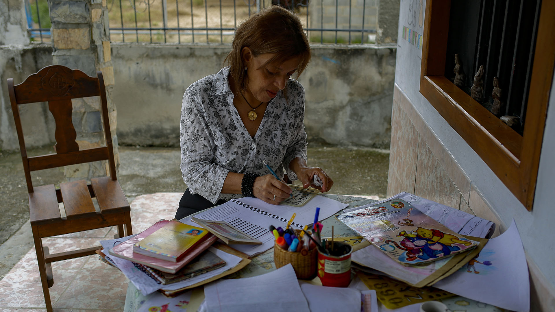 La profesora Martha Susana Guevara coloca actividades en el cuaderno de un alumno en Montalbán, estado de Carabobo, Venezuela, el 9 de julio de 2022. (Foto de Pedro Rances Mattey / AFP)