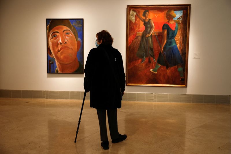 Una mujer observa el "Retrato" de Kostiantyn Yeleva y "En la galería de tiro" de Semen Yoffe durante la inauguración de la exposición de pintura vanguardista ucraniana con medio centenar de cuadros traídos del Museo Nacional de Arte y del Museo de Teatro,