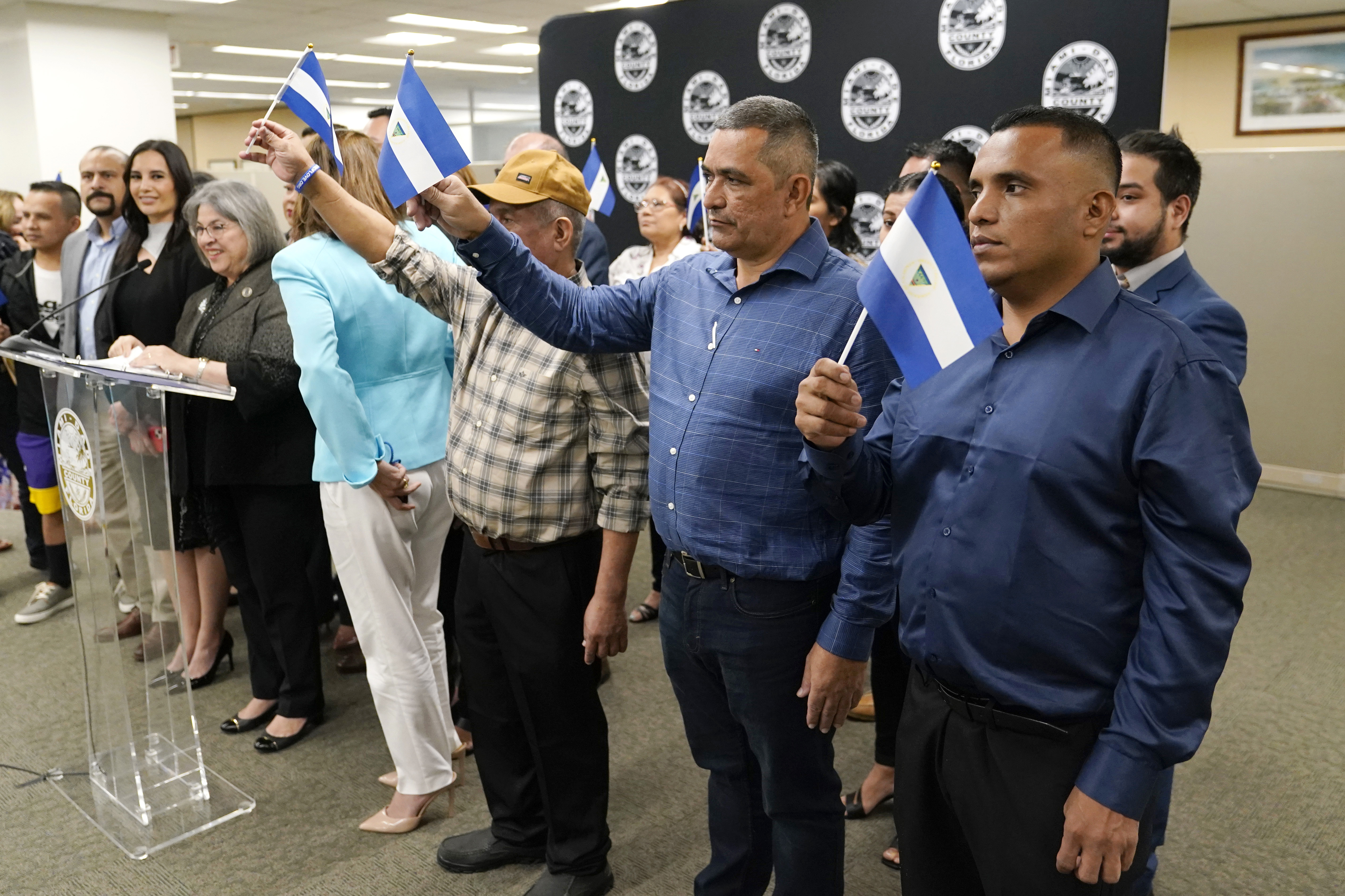 Isaías Martinez Rivas, el primer hombre vestido de azul desde la derecha, permanece parado junto a otros opositores políticos de Nicaragua expulsados de su país durante una rueda de prensa en la oficina de la alcaldesa del condado de Miami-Dade (AP Foto/Lynne Sladky)