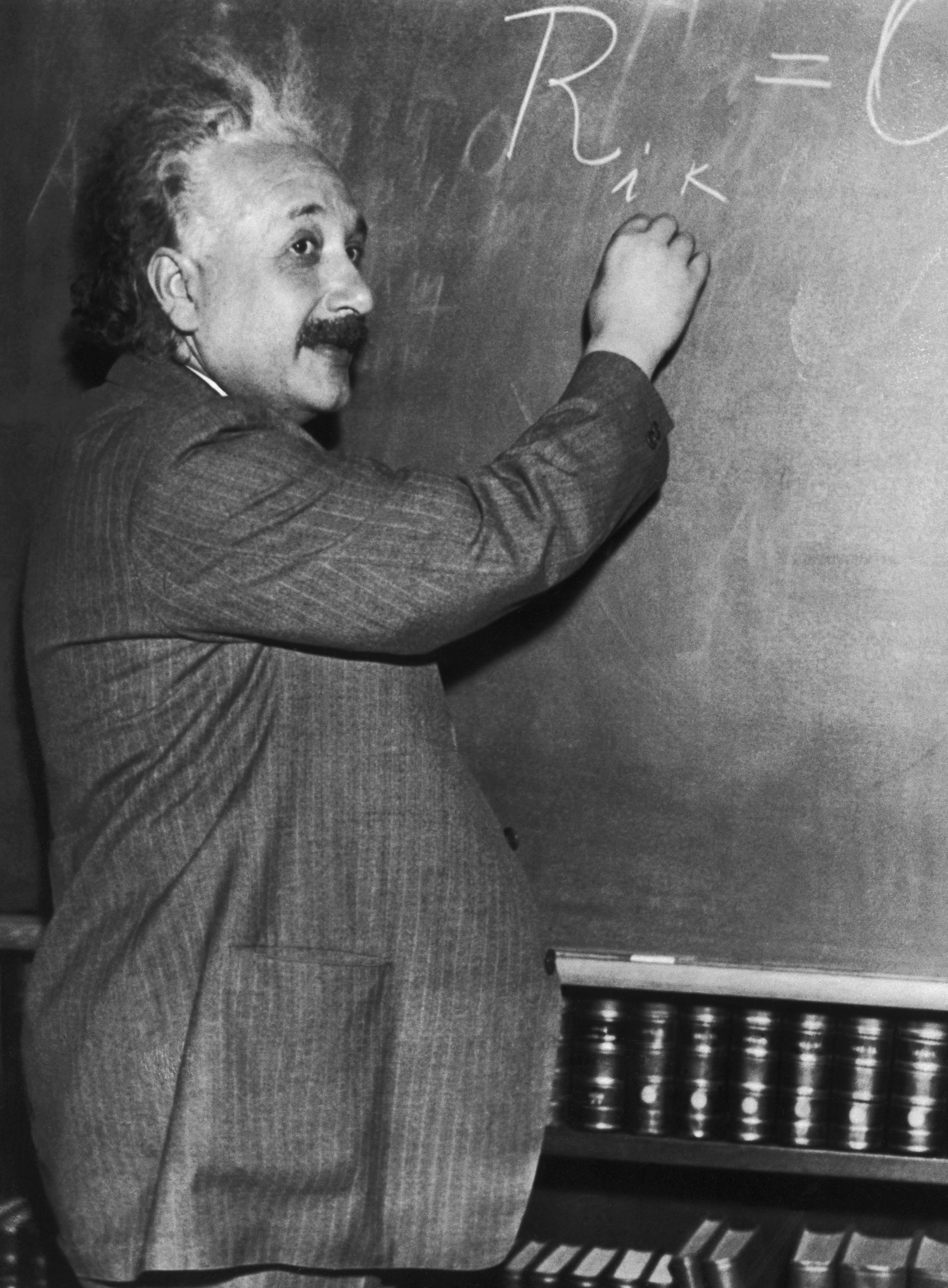 Albert Einstein demonstrates mathematical formulas on a blackboard in front of California scientists.