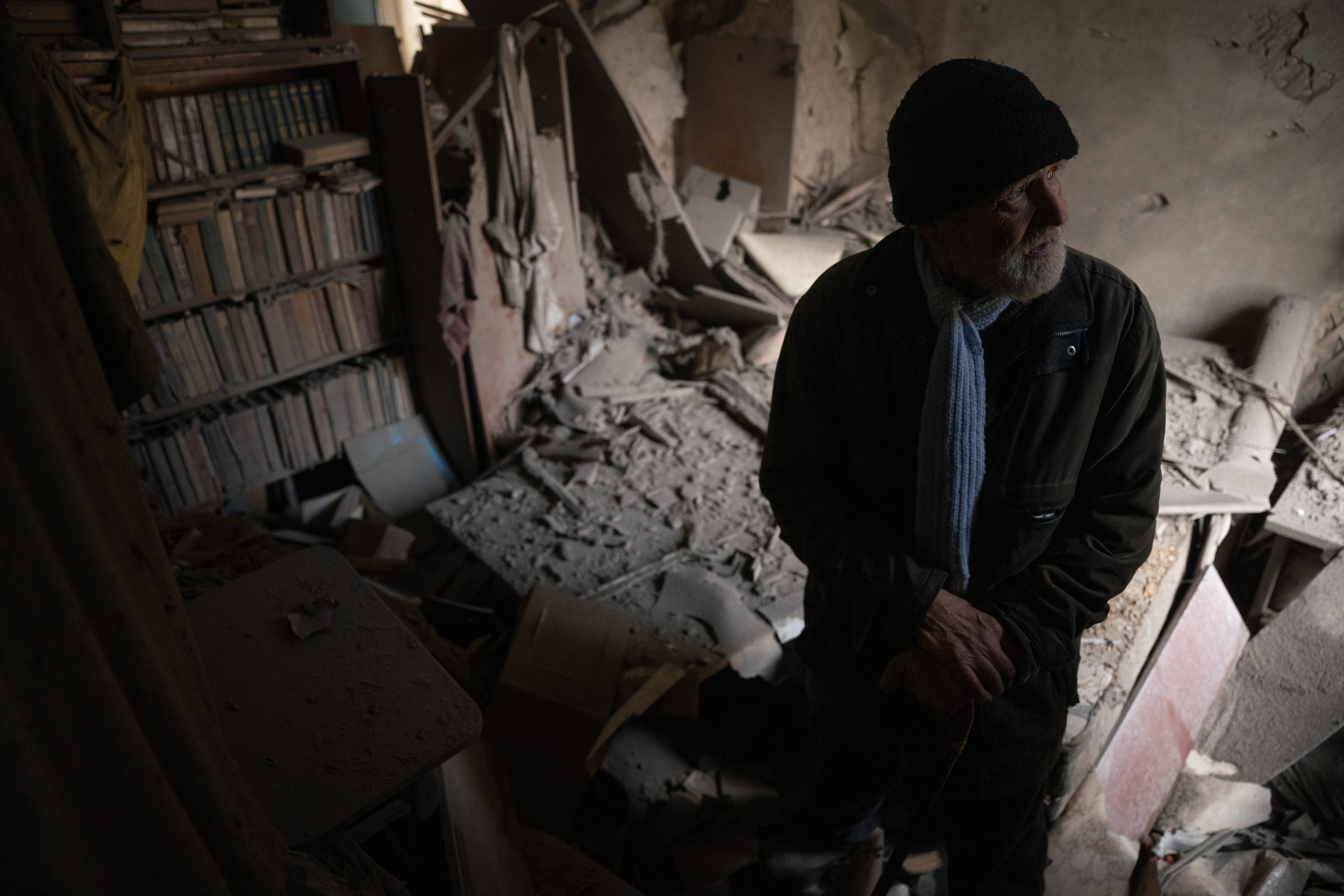 Valeriy Belyachenko, de 84 años, residente de Bucha, mira a travez del hueco que dejo el misil que atravesó la fachada de su hogar.
