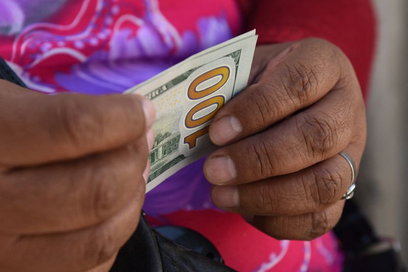 Un comerciante informal de divisas sostiene billetes de dólares estadounidenses en una calle, en La Paz, Bolivia. 6 de marzo 2023. REUTERS/ Claudia Morales
