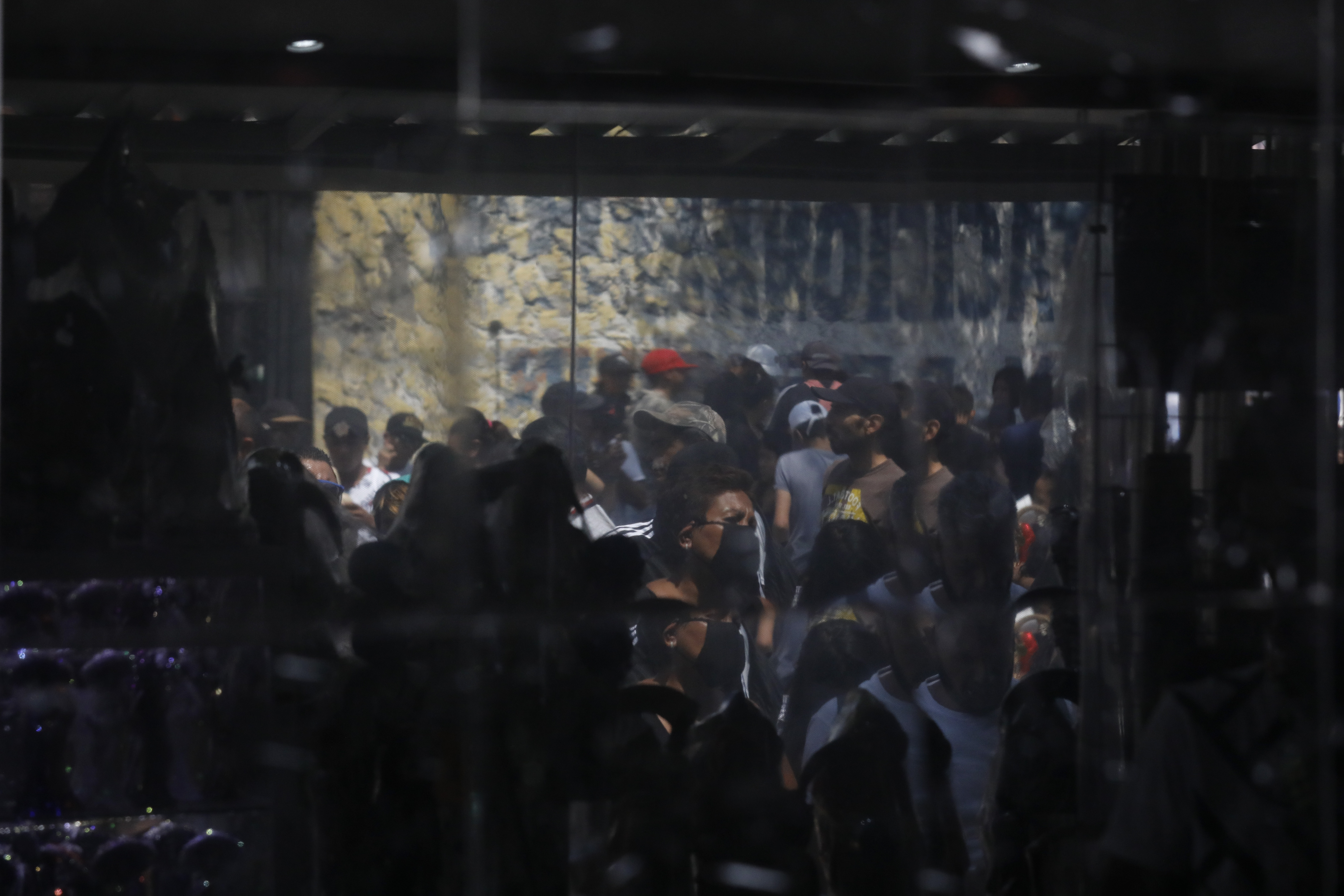Las personas se reflejan en una pared mientras esperan afuera para visitar un altar a la Santa Muerte. (Foto: AP / Rebecca Blackwell)
