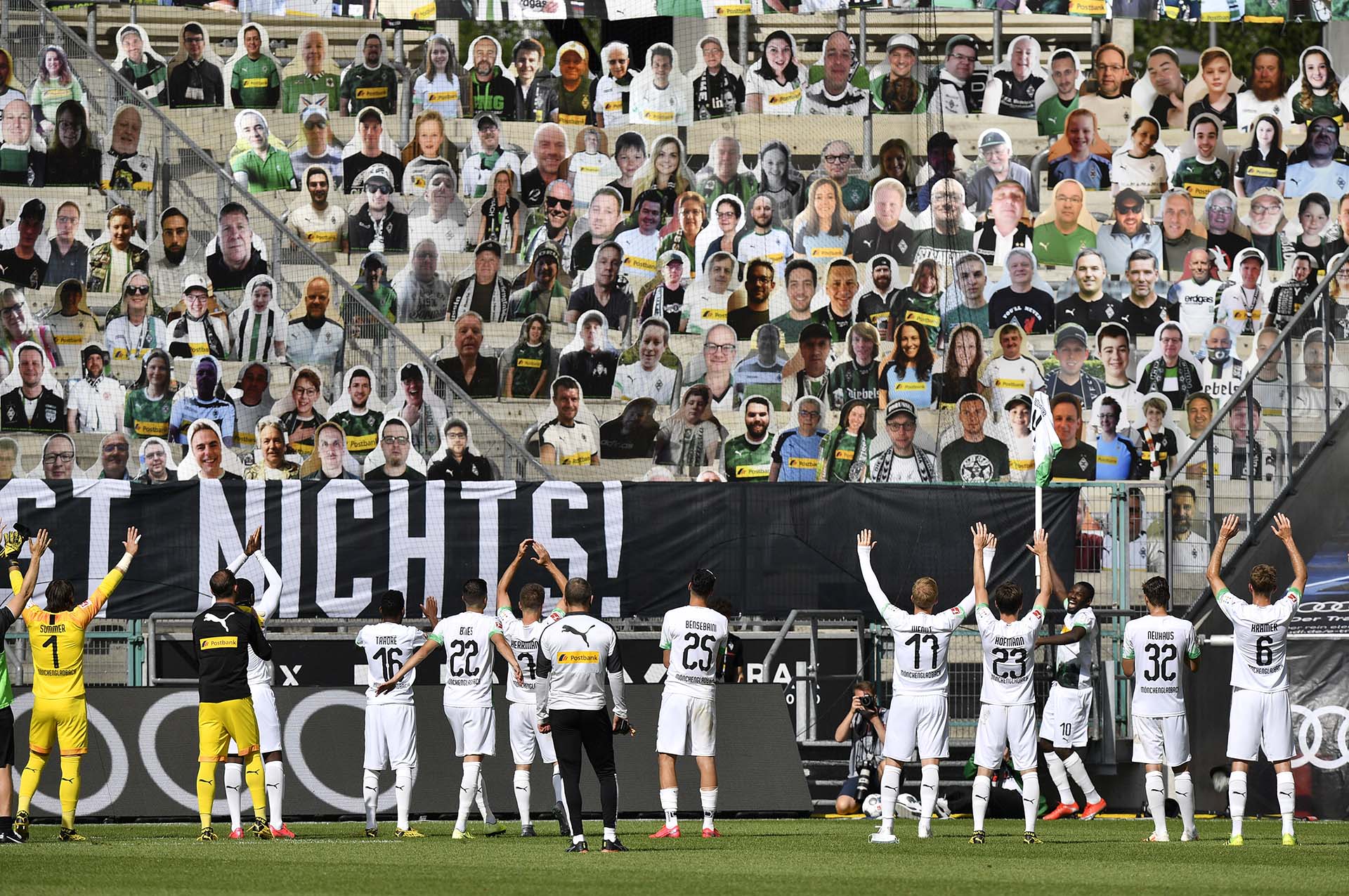 Los jugadores del Borussia Moenchengladbach celebran frente a fotos de sus hinchas colocadas en su estadio sin público, en el regreso de la Bundesliga después de la suspensión por la pandemia (31 de mayo)