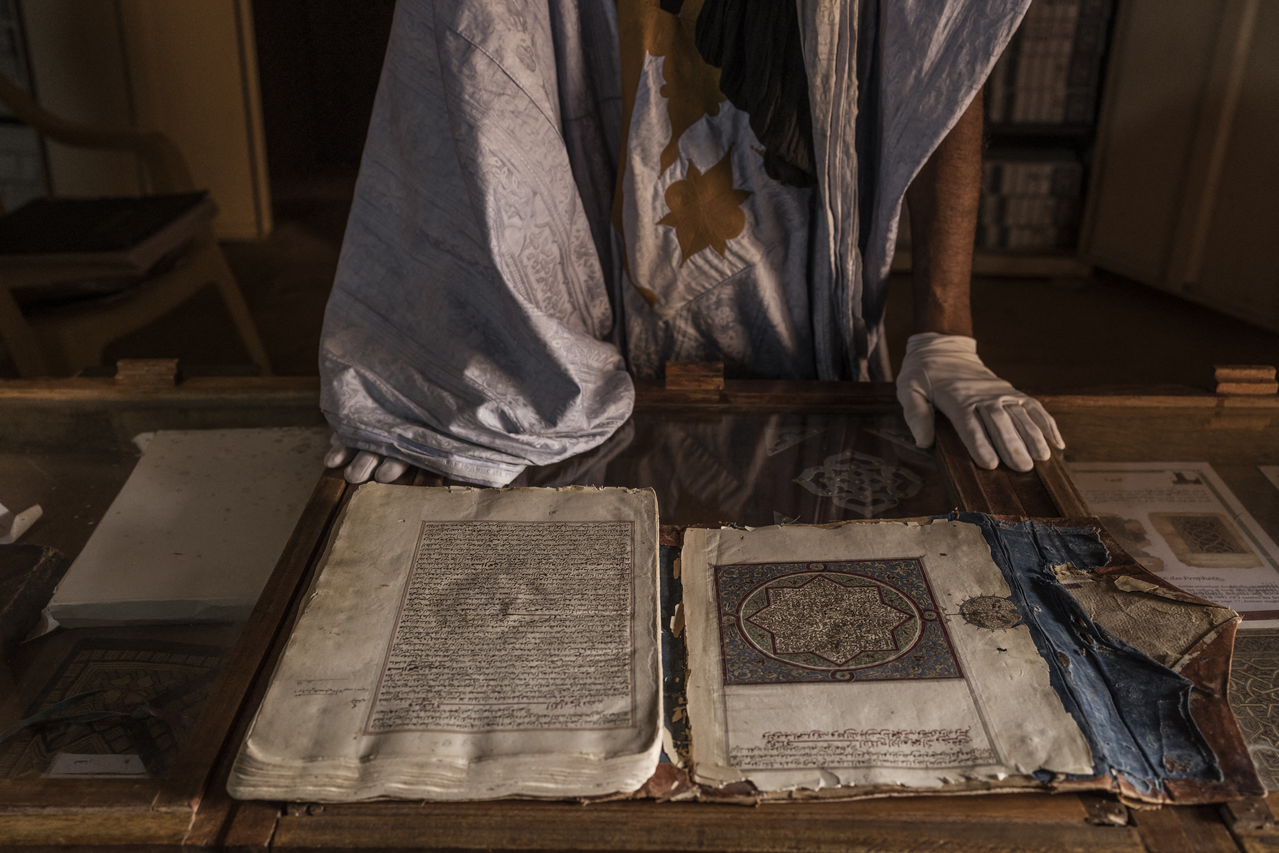 Abdullah Habbot, de 45 años, junto a un manuscrito en un escaparate de su biblioteca, fundada por su familia hace más de 200 años, en Chinguetti, el 16 de marzo de 2023, donde se conservan otros 1400 manuscritos de propiedad privada (Foto de MARCO LONGARI / AFP )