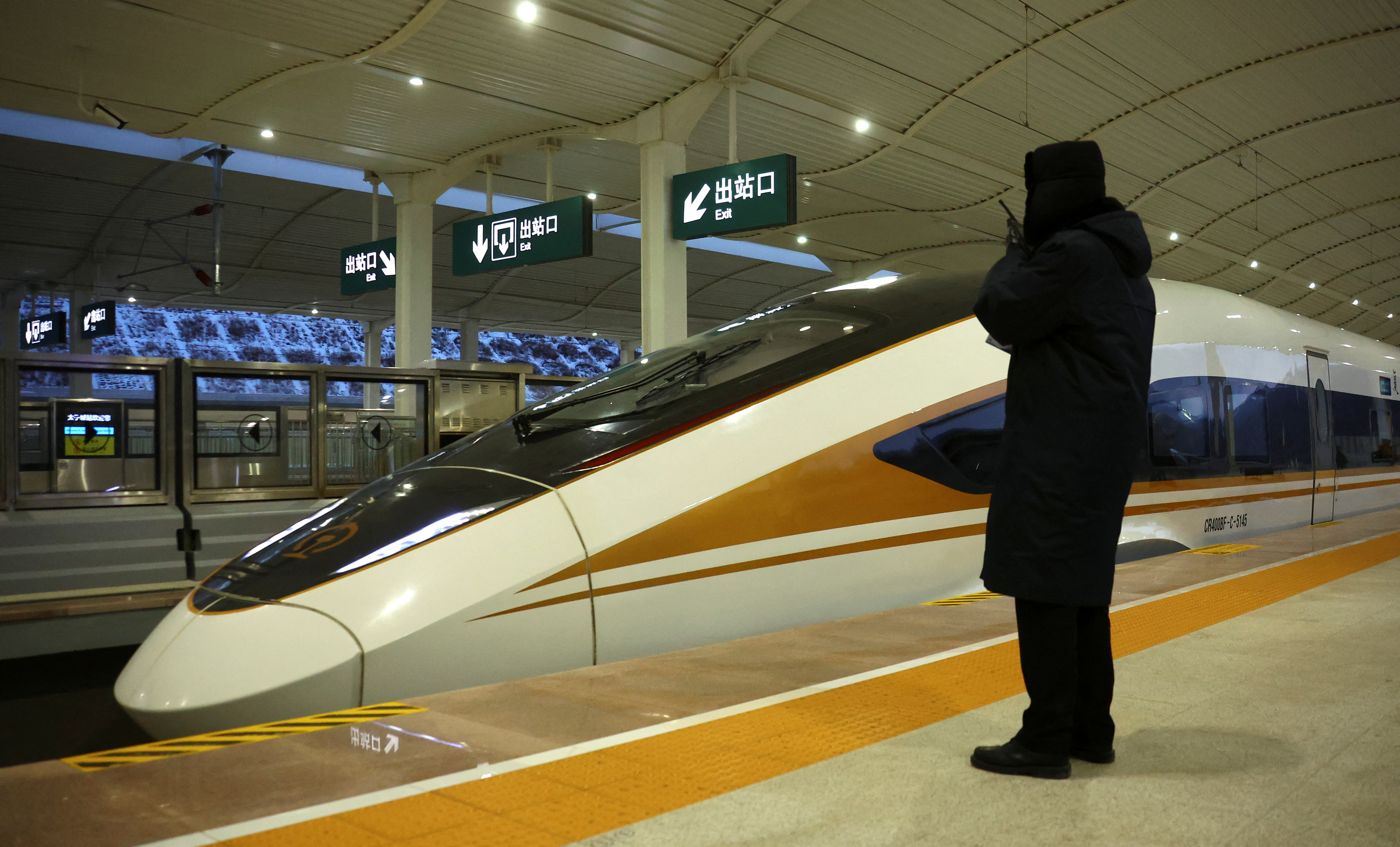 Chinese railway staff stands beside a high-speed train at Zhangjiakou cluster train station inside a closed loop area designed to prevent the spread of the coronavirus disease (COVID-19) in Zhangjiakou, China January 25, 2022. REUTERS/Fabrizio Bensch