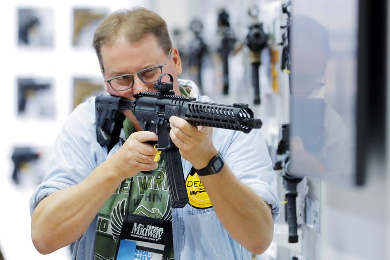 Un hombre manipula un rifle dentro del stand de Sig Sauer durante la reunión anual de la Asociación Nacional del Rifle (NRA)