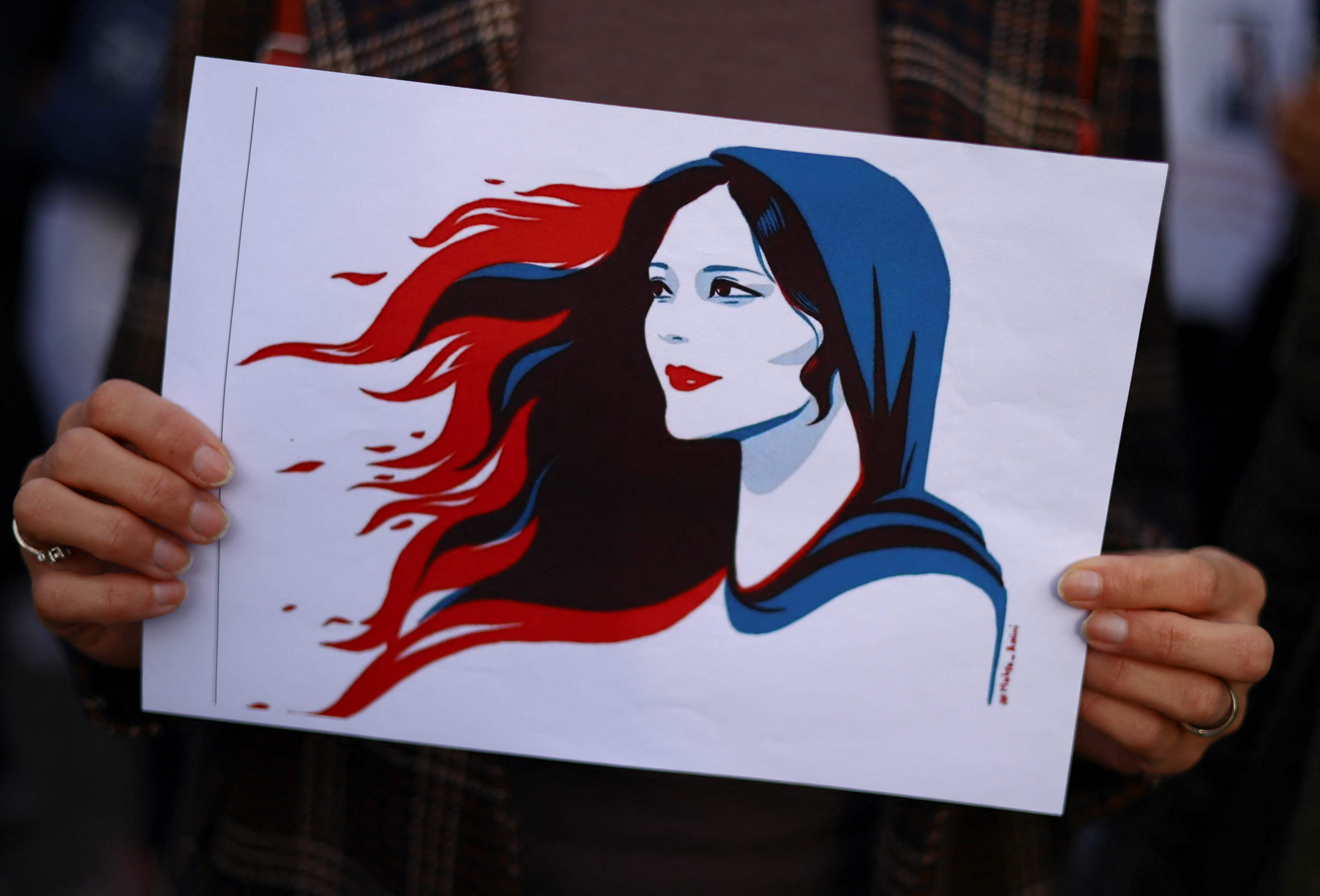 Una persona sostiene una obra de arte que representa a Mahsa Amini mientras participan en una protesta tras su muerte (REUTERS)