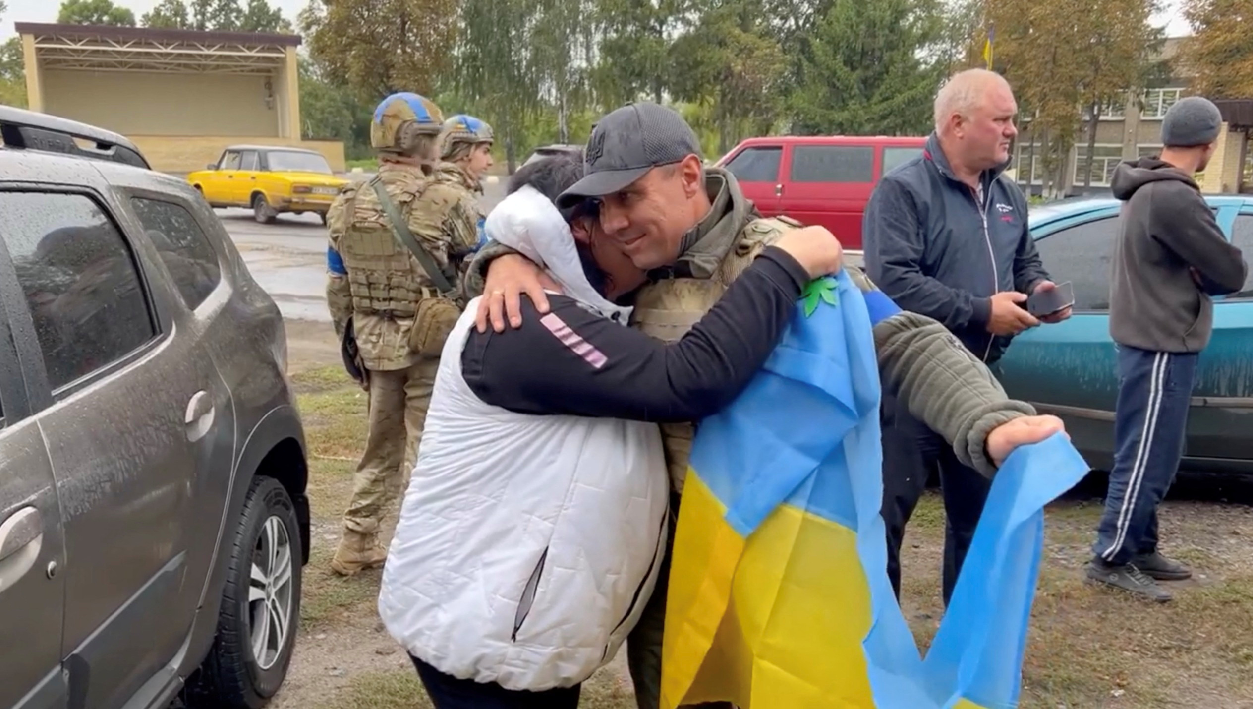El alcalde del distrito de Derhachi, Vyacheslav Zadorenko, abraza a un residente mientras sostiene una bandera ucraniana en Kozacha Lopan, región de Kharkiv (Facebook/Vyacheslav Zadorenko/vía REUTERS)