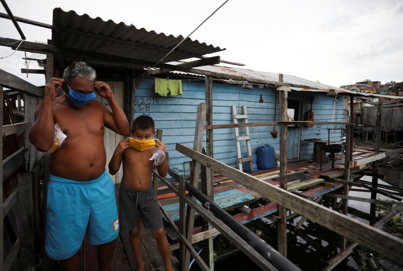Un hombre y un niño ajustándose sus máscaras en una barriada pobre en Manaos, Brasil, en medio de la pandemia de coronavirus (REUTERS/Bruno Kelly)