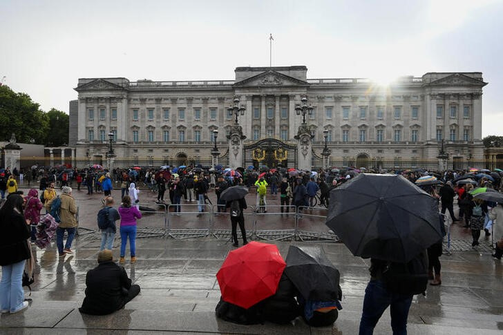 Antes de la muerte, las personas se refugian bajo sus paraguas mientras se reúnen frente al Palacio de Buckingham, luego de una declaración del Palacio sobre las preocupaciones por la salud de la Reina Isabel de Gran Bretaña, en Londres, Inglaterra, el 8 de septiembre de 2022 (REUTERS/Toby Melville)