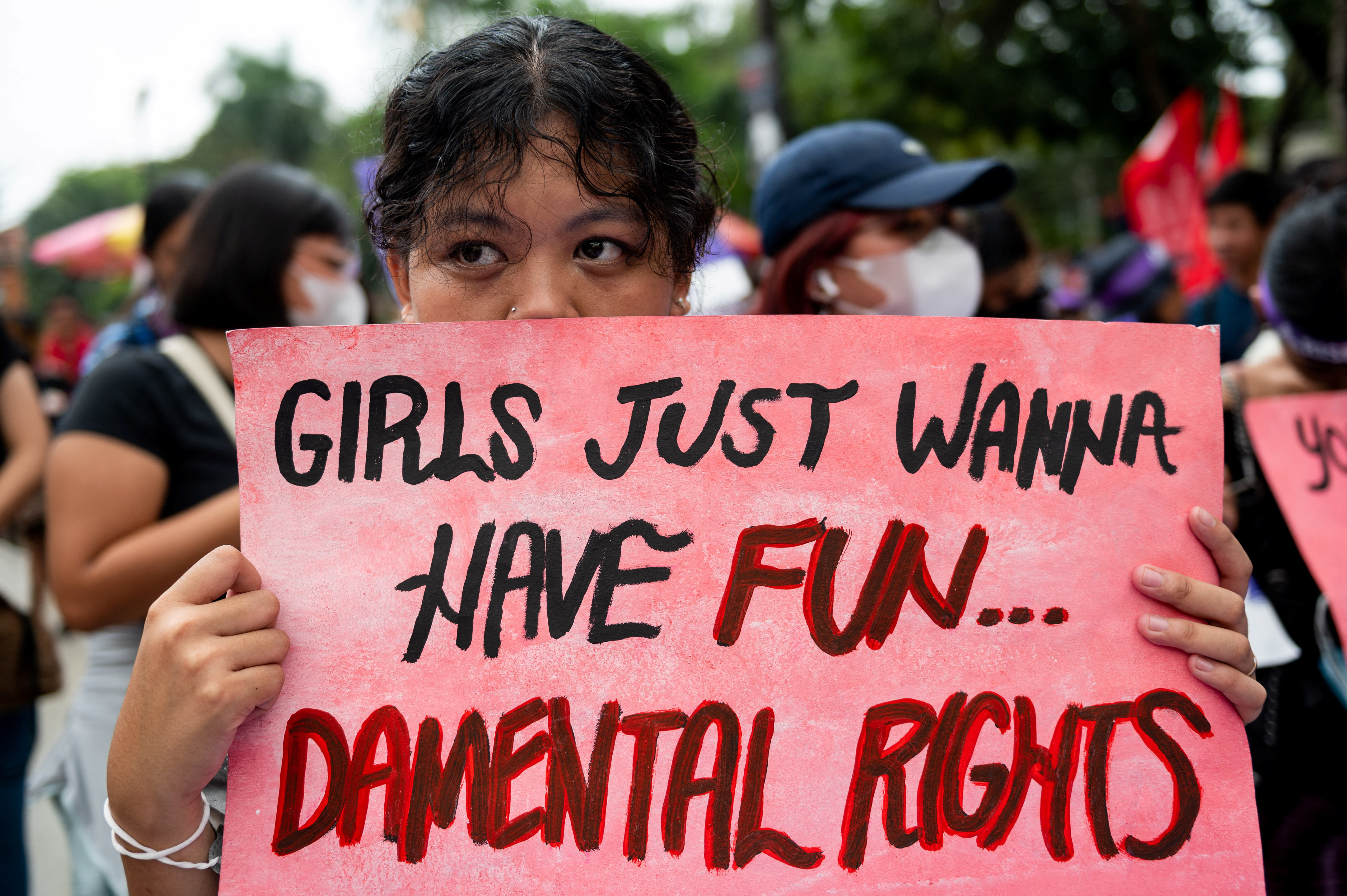 Una activista muestra un cartel que dice "Las chicas solo quieren divertirse... derechos mentales" durante la marcha por el 8M en Filipinas.