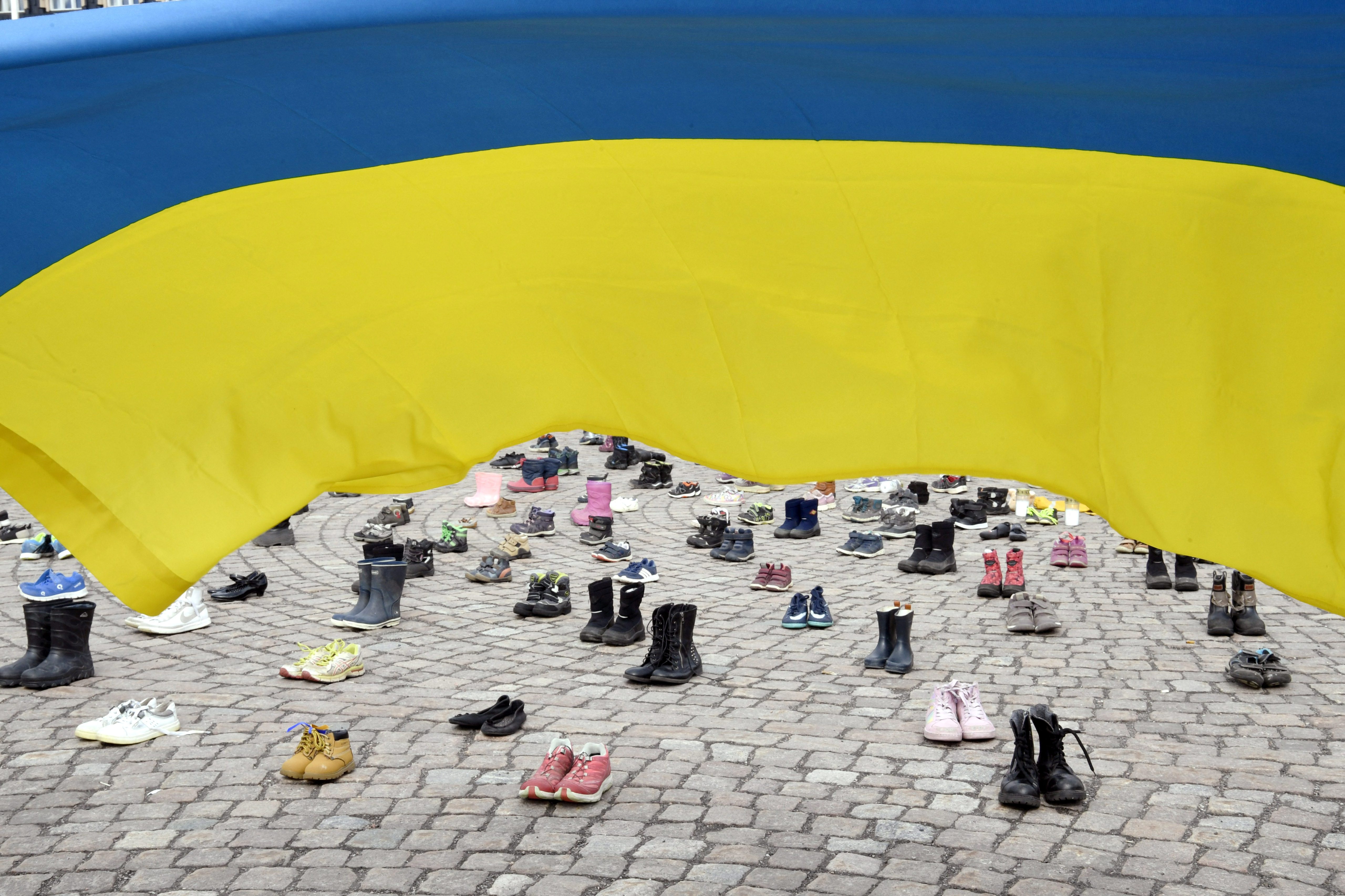 Zapatos, botas y velas se colocan durante una manifestación organizada por la Asociación Ucraniana en Finlandia para honrar la memoria de los niños muertos en medio de la invasión rusa en la ciudad ucraniana de Mariupol, en Helsinki, Finlandia, el 10 de abril de 2022. Lehtikuva/Jussi Nukari vía REUTERS