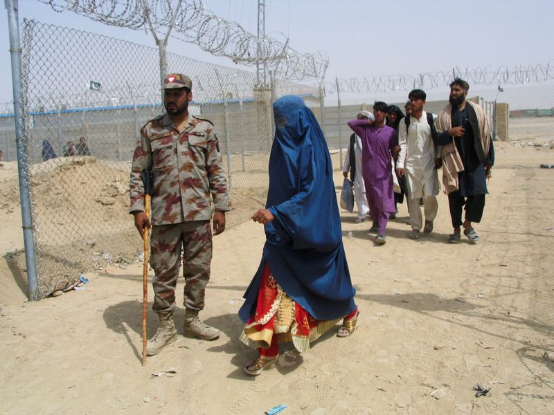 Una mujer con una burqa pasa frente a un soldado paramilitar de Pakistán en un punto fronterizo con Afganistán
REUTERS/Saeed Ali Achakzai