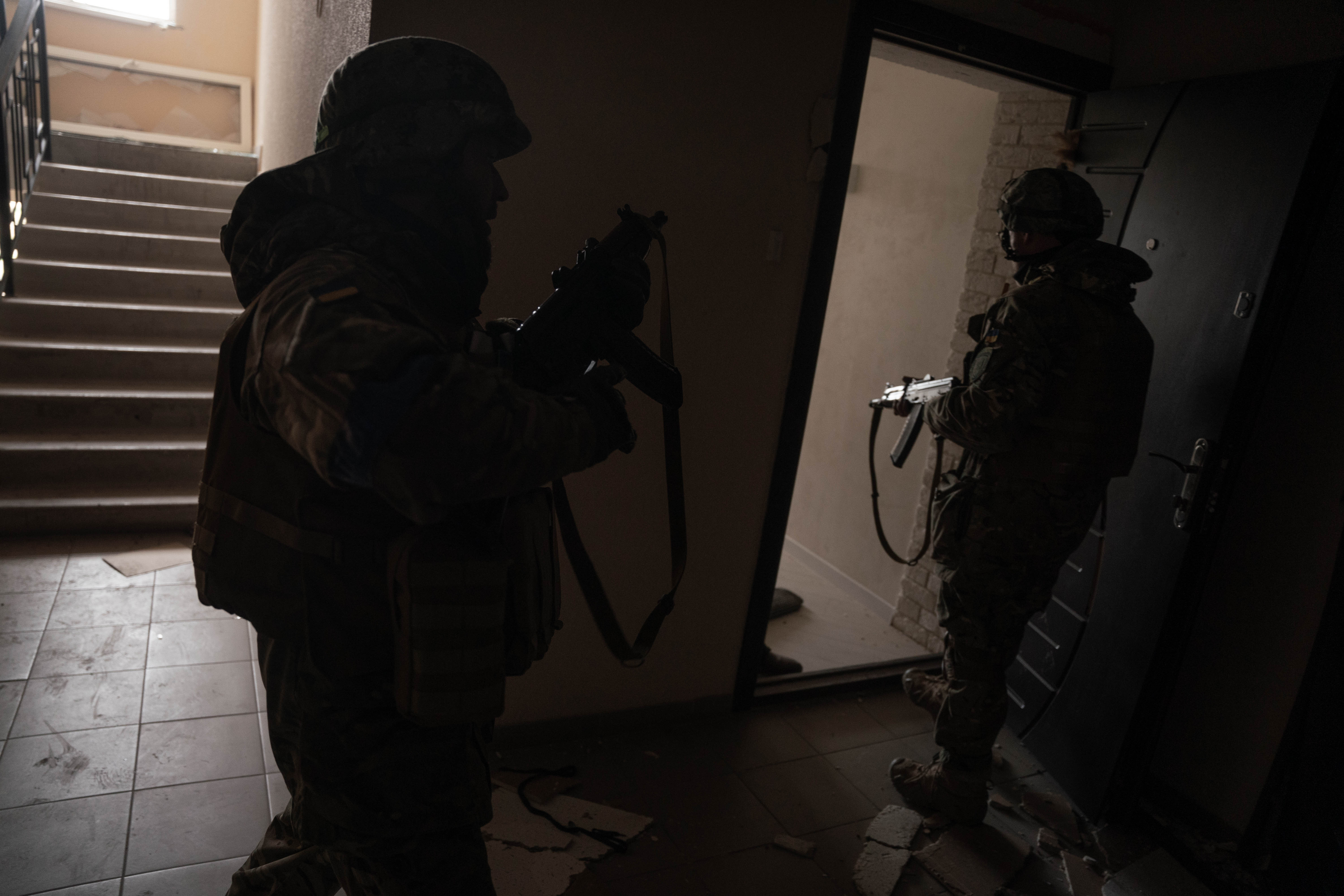 Militares ucranianos ingresan a uno departamento mientras realizan tareas de vigilancia en Bucha.