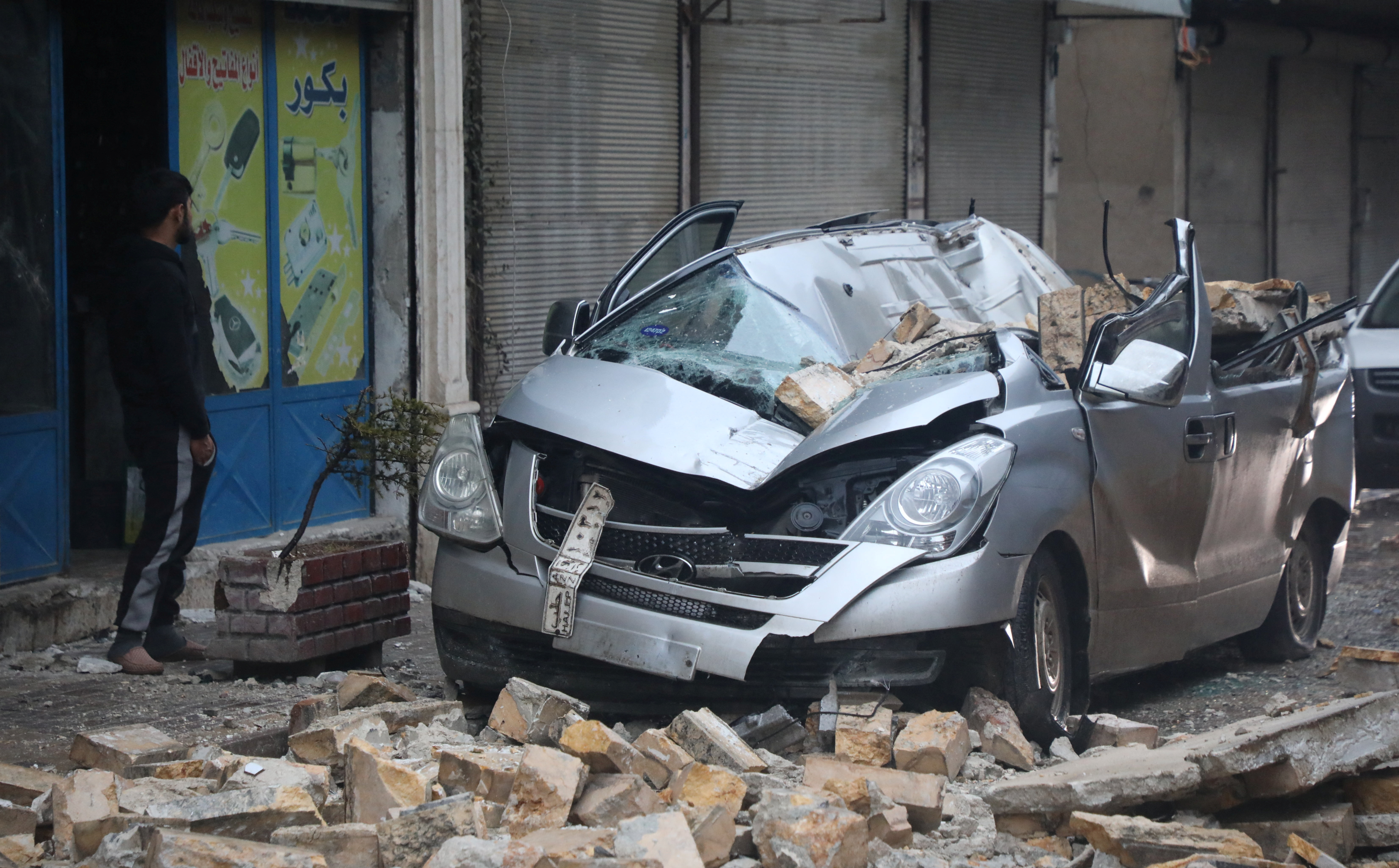 Un hombre parado cerca de un vehículo dañado, luego de un terremoto, en Azaz, Siria, controlada por los rebeldes.

