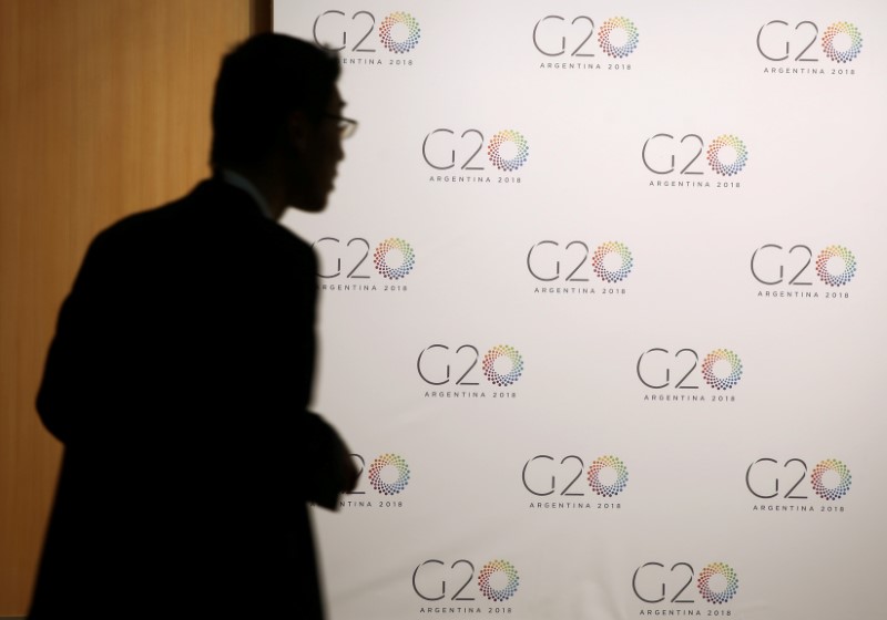 Un hombre camina cerca de un afiche con el logo de las reuniones del G-20 en Buenos Aires en 2018 (Foto: Reuters)