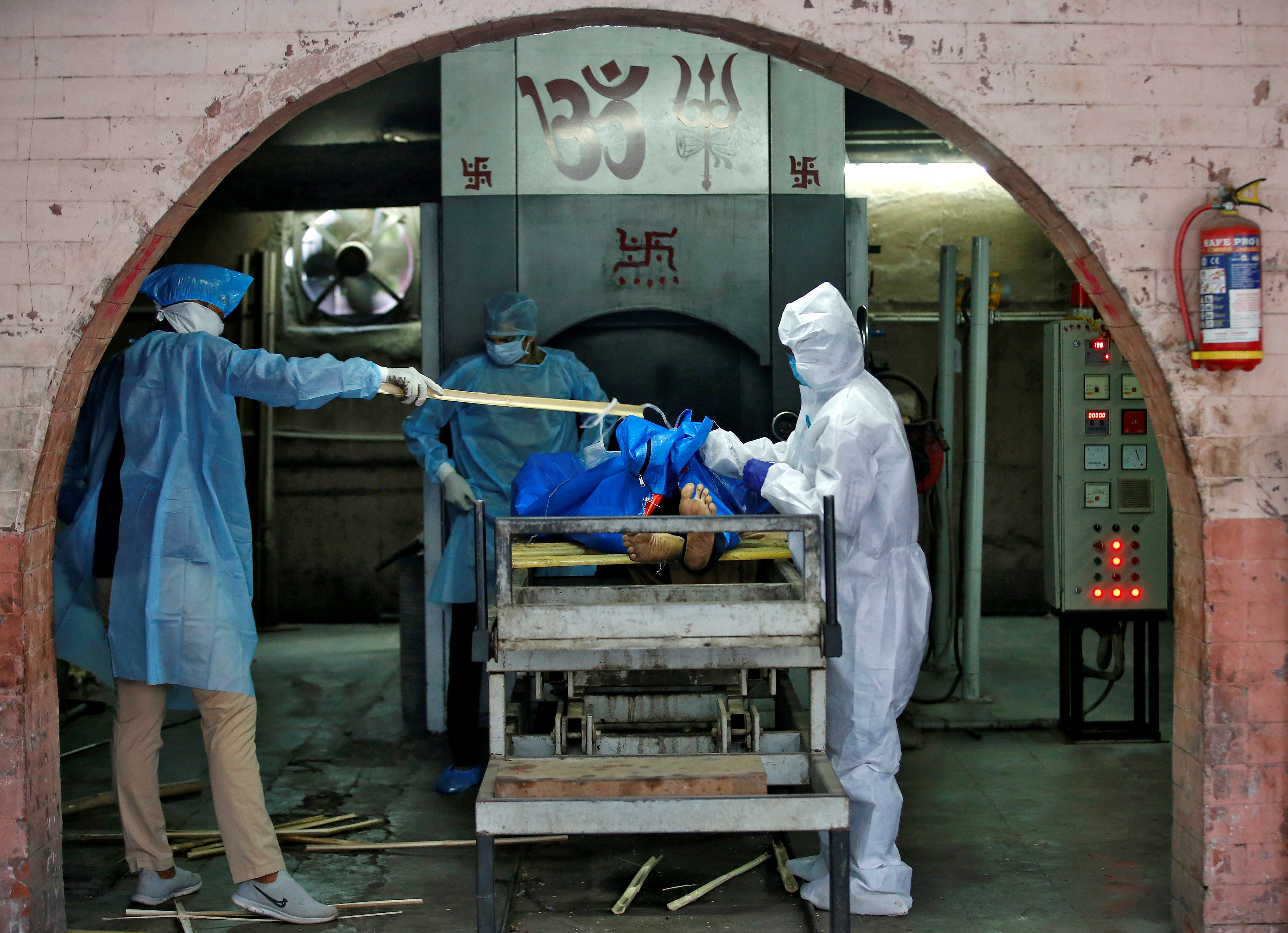 Trabajadores municipales con equipo de protección se preparan para incinerar el cuerpo de un hombre, que murió debido a la enfermedad coronavirus (COVID-19), en un crematorio en Ahmedabad, India, el 22 de abril de 2020. REUTERS/Amit Dave