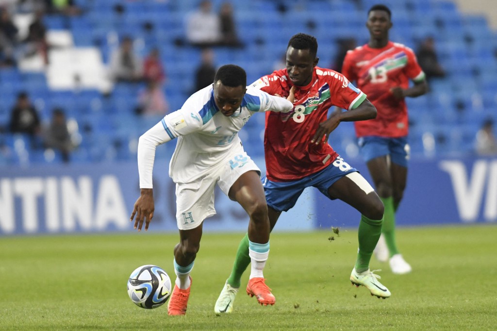 El defensor de Honduras Felix Garcia  cubre la pelota ante el mediocampista de Gambia Salifu Colley (Andres Larrovere / AFP)