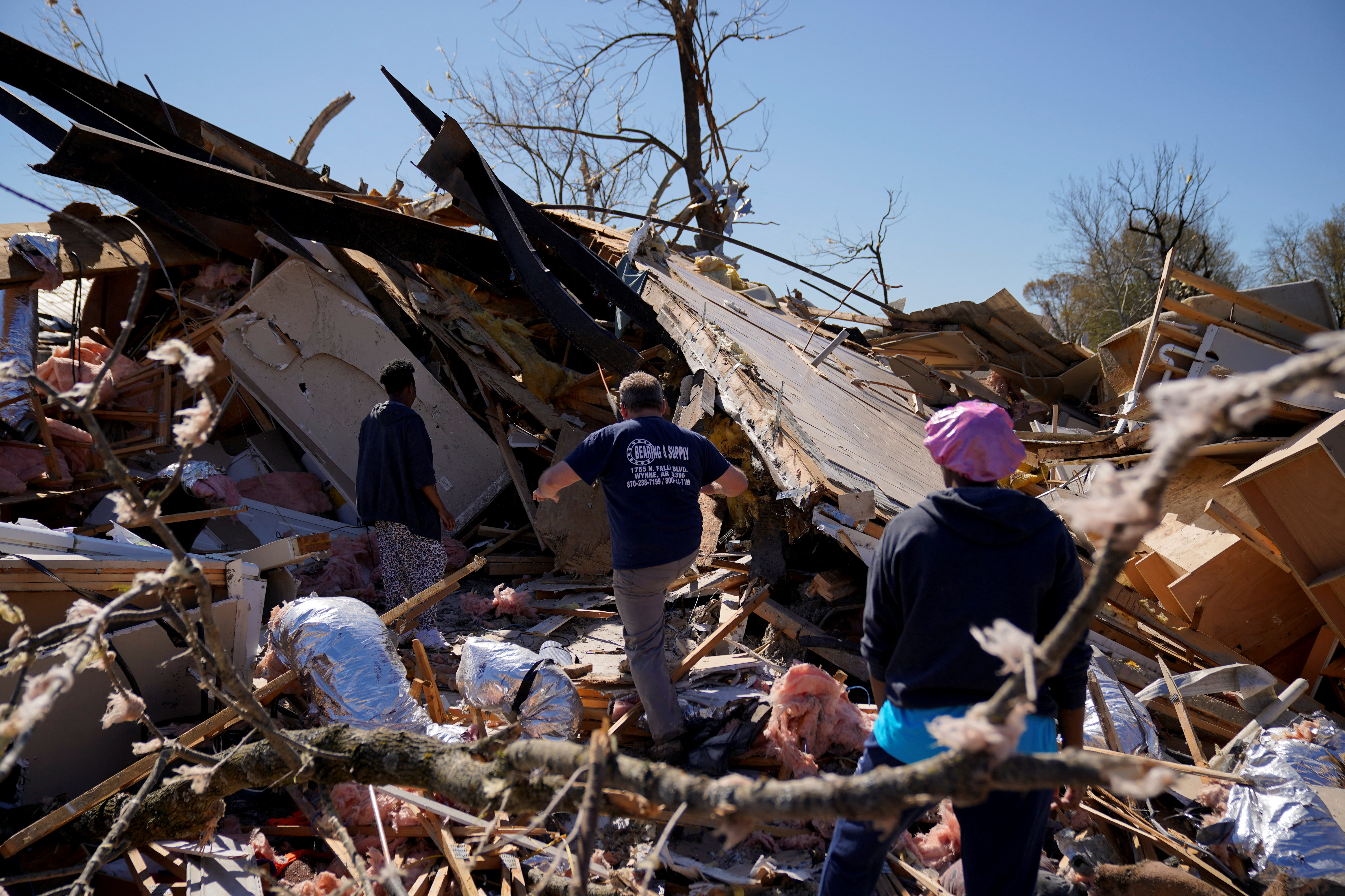 Ann Wooten, de 36 años, su hija Olivia Wooten, de 13, y su casero Steve Headley, de 51, suben a los escombros de la casa de Wooten para recuperar sus pertenencias tras el paso de un tornado en Wynne, Arkansas (REUTERS/Cheney Orr)