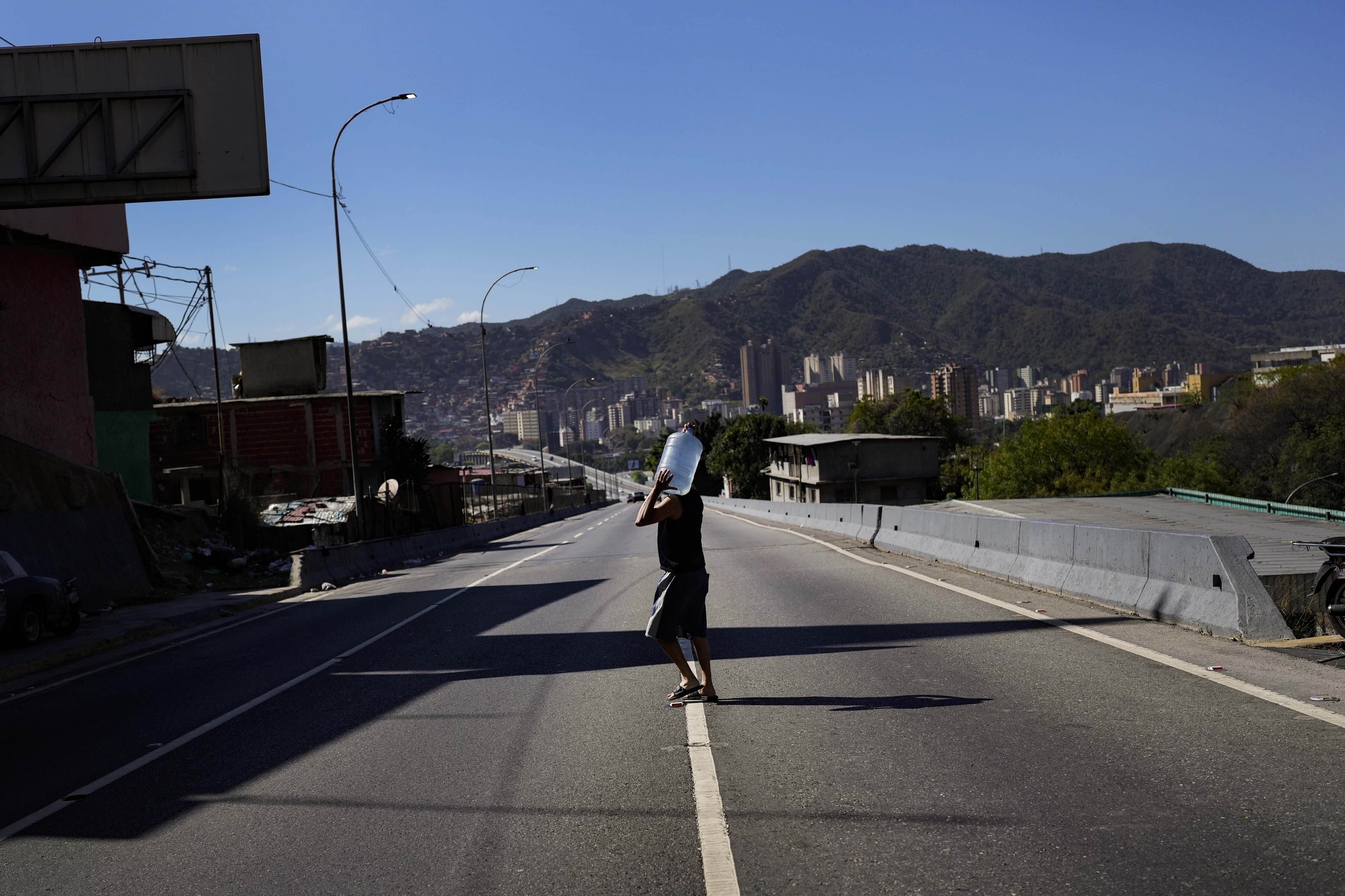 Un hombre carga una garrafa de agua recogida en un torrente en una montaña, en Caracas, Venezuela, el 19 de marzo de 2023. (AP Foto/Matías Delacroix)
