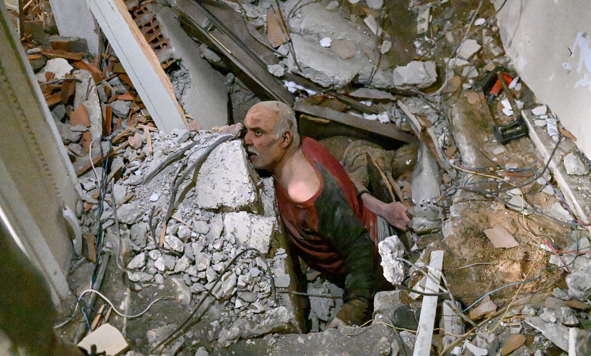 Un hombre atrapado entre los escombros espera que los rescatistas puedan sacarlo. A su lado yace el cuerpo de una víctima (AFP)