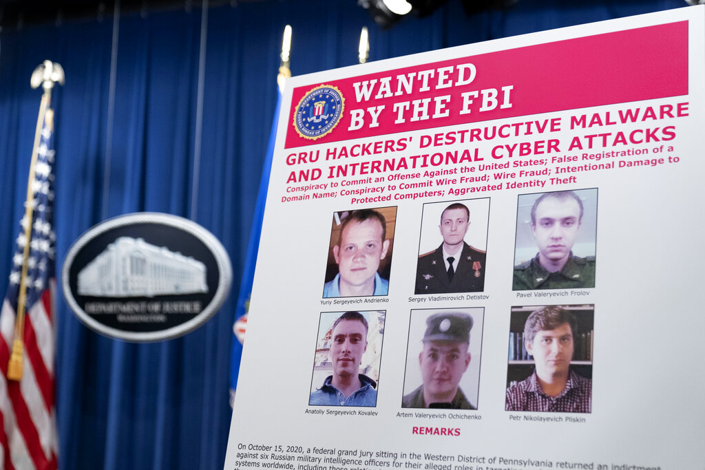 Un cartel que muestra seis oficiales de la inteligencia militar rusa buscados se exhibe antes de una conferencia de prensa en el Departamento de Justicia (AP Photo/Andrew Harnik)