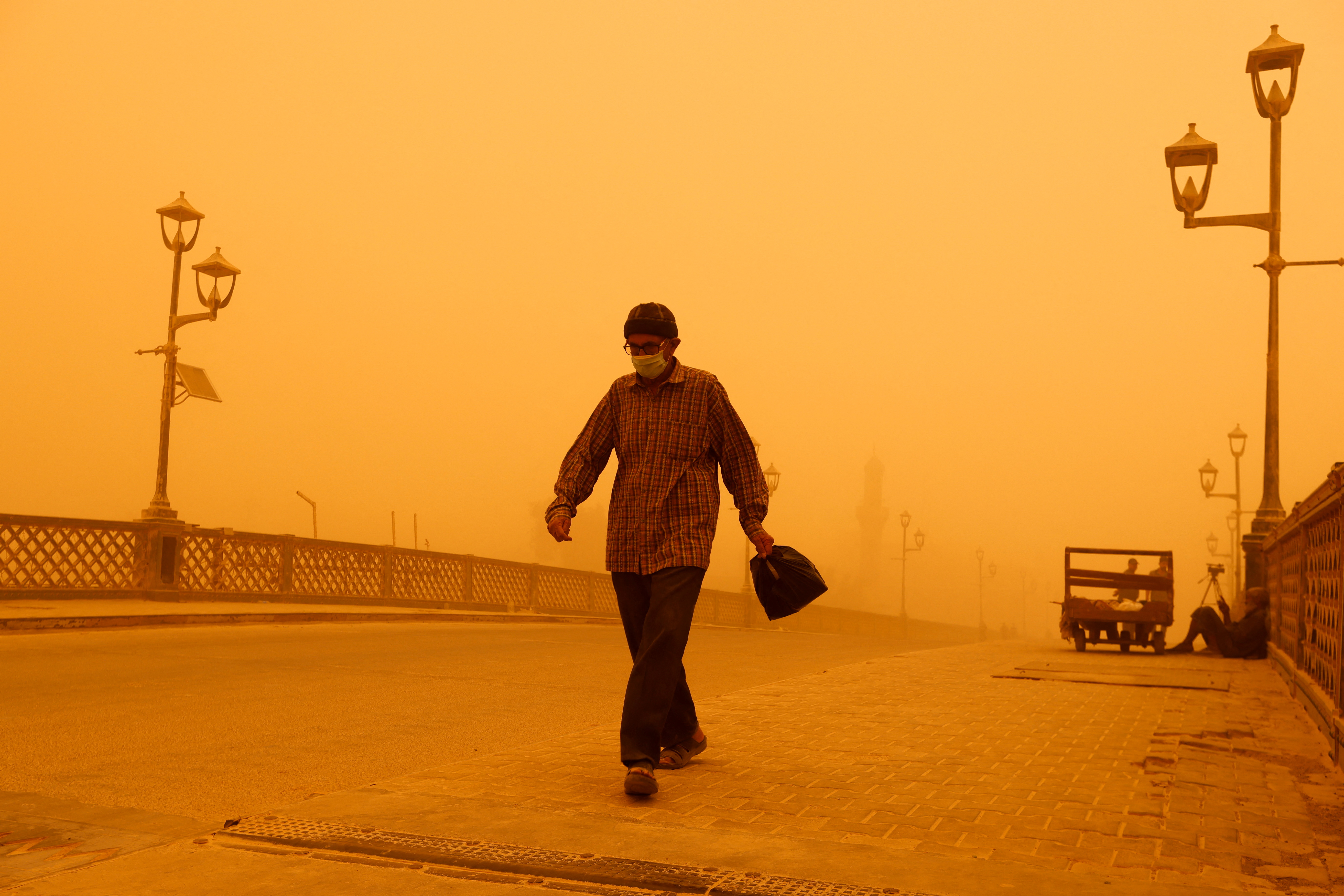 Un hombre con una máscara camina sobre un puente durante una tormenta de arena en Bagdad, Irak, el 16 de mayo de 2022. REUTERS/Ahmed Saad
