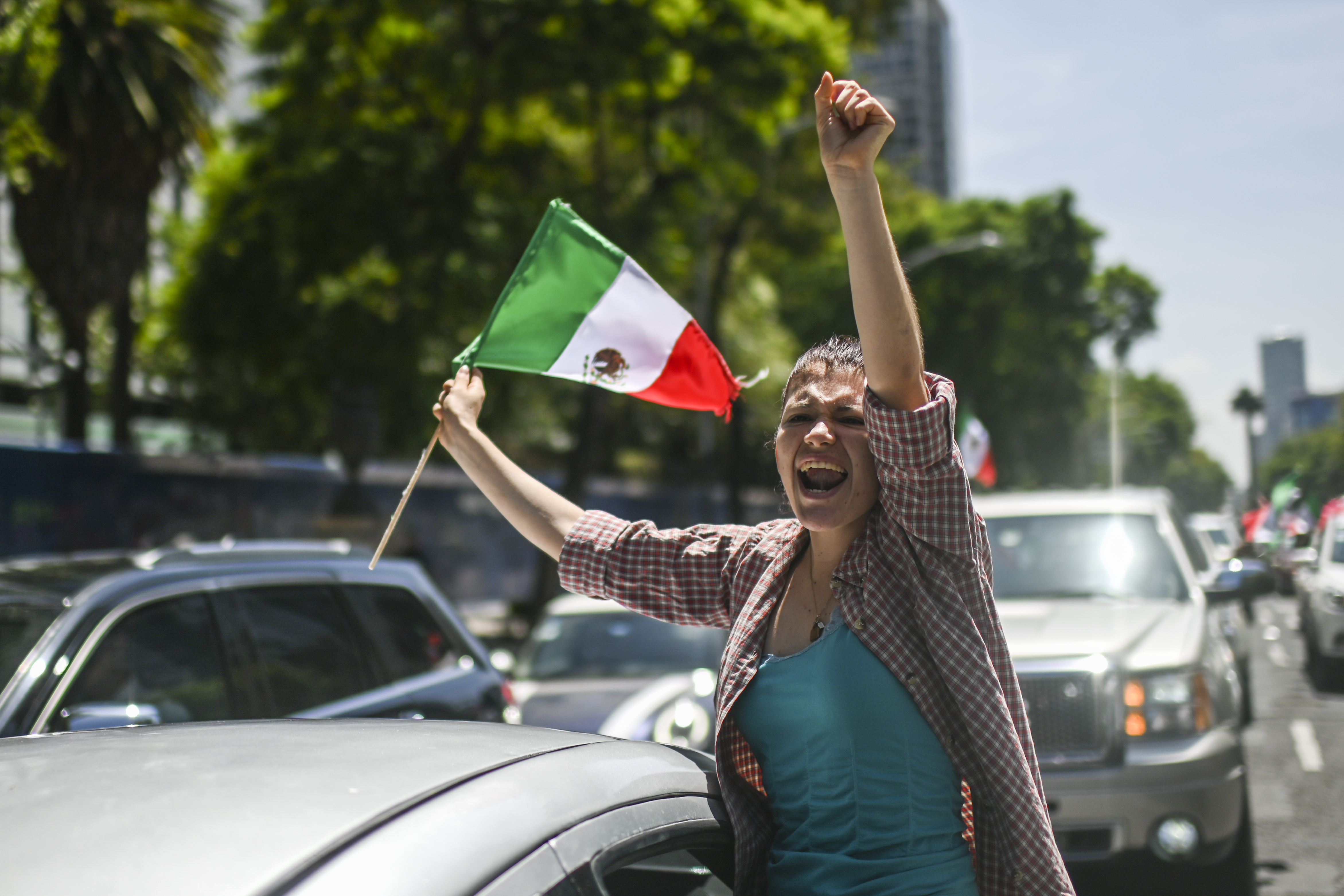 Una manifestante hace un gesto mientras sostiene una bandera mexicana durante una caravana para protestar contra el gobierno del presidente mexicano Andrés Manuel López Obrador, en la Ciudad de México, el 28 de junio de 2020, en medio de la nueva pandemia de coronavirus COVID-19. (Foto por Pedro PARDO / AFP)