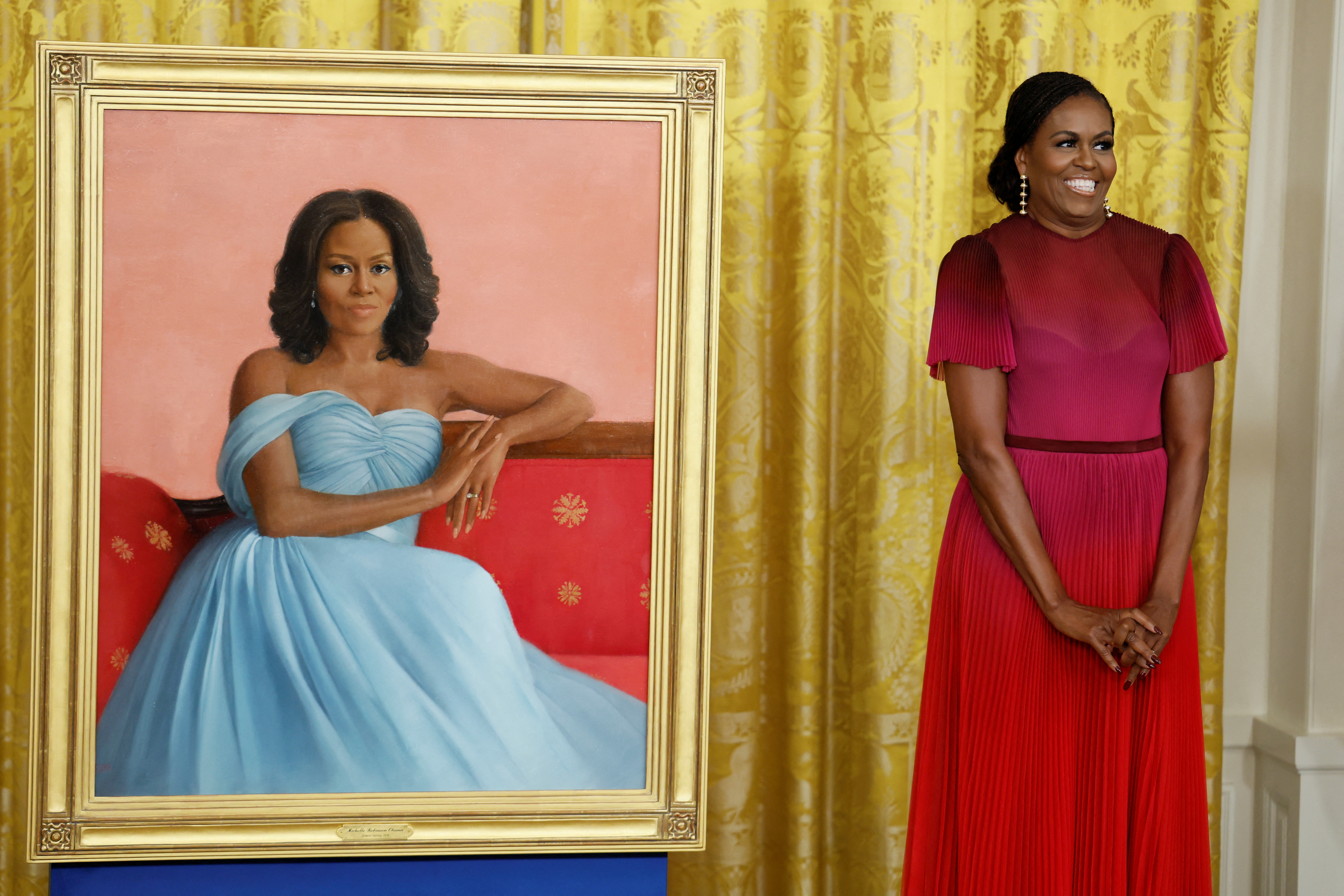 Former U.S. first lady Michelle Obama poses next to her official White House portrait, painted by Sharon Sprung, in the East Room of the White House, in Washington, U.S., September, 7, 2022. REUTERS/Evelyn Hockstein