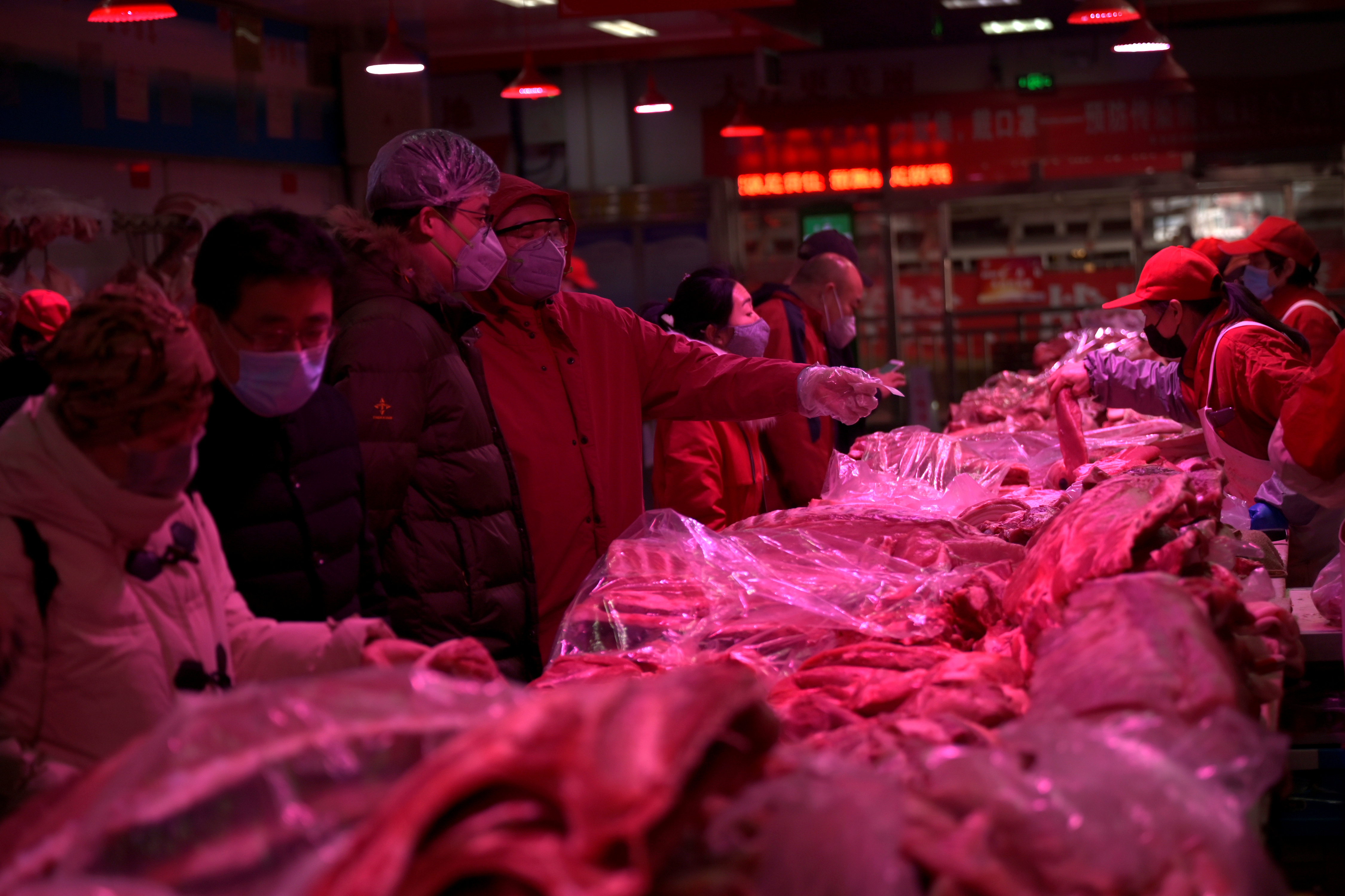 Clientes con máscaras protectoras compran carne de cerdo en el mercado mayorista de Xinfadi (Reuters)