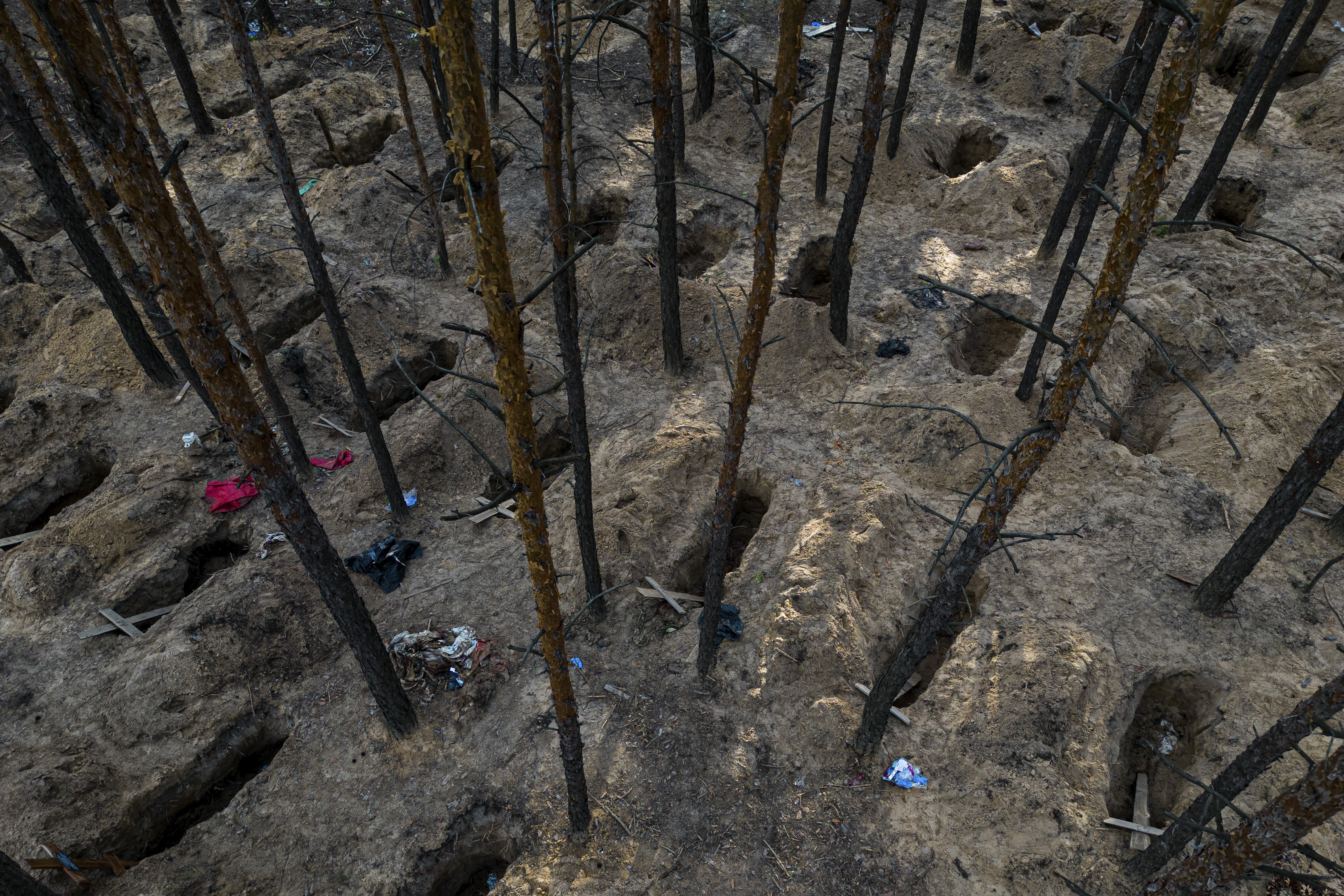 Tumbas no identificadas de civiles y soldados ucranianos son exhumadas en un cementerio en la recién retomada zona de Izium, Ucrania, el lunes 19 de septiembre de 2022. (AP Foto/Evgeniy Maloletka)