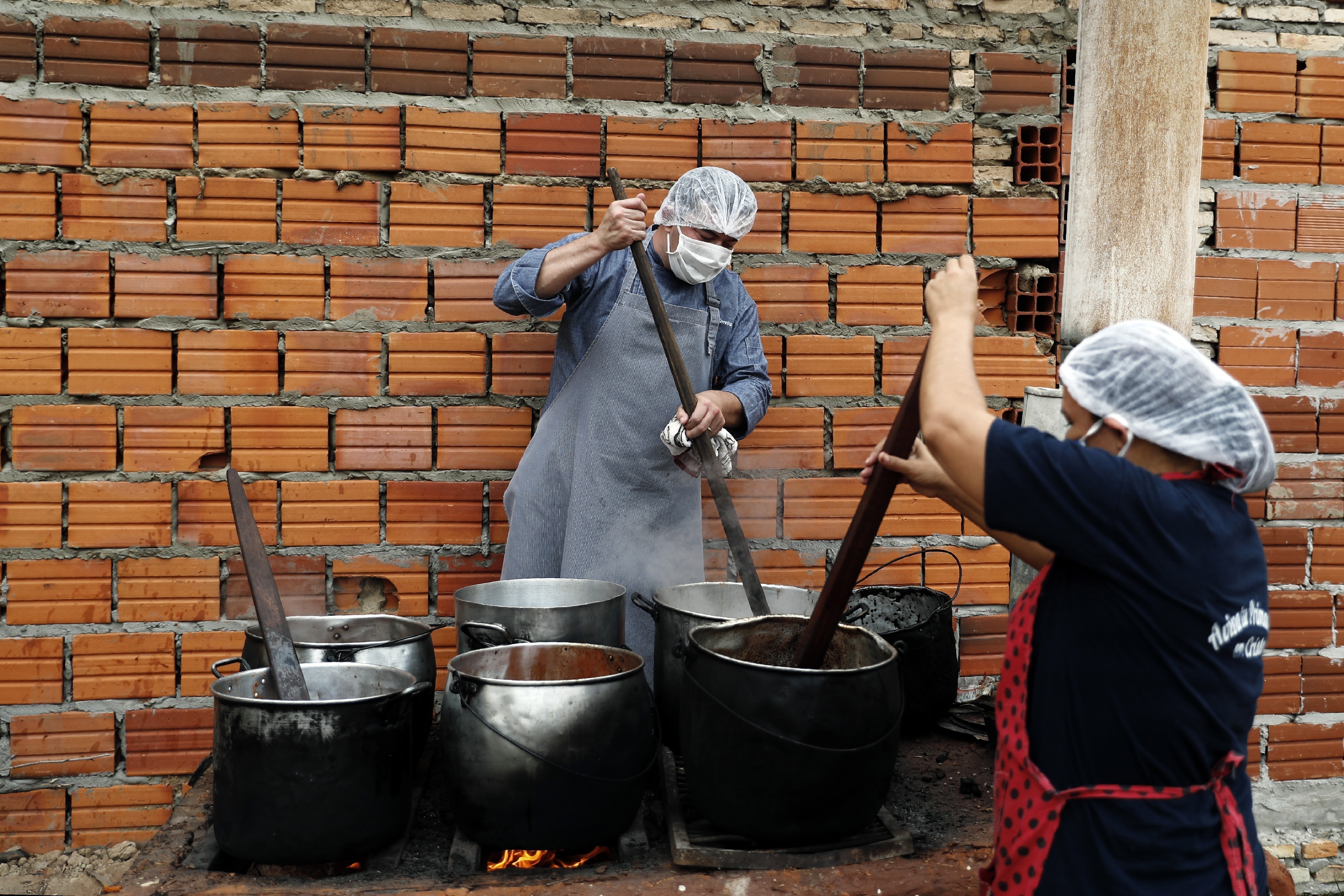 Walter Ferreira, a la izquierda, y Laura Dure preparan estofado en un comedor social que alimenta a unas 300 personas cada día en Luque, Paraguay, el lunes 11 de mayo de 2020.  En toda la región, se espera que casi 30 millones de personas más se vean en “situaciones de pobreza” y otros 16 millones en pobreza extrema, según las estimaciones de Naciones Unidas. (AP Foto/Jorge Sáenz)
