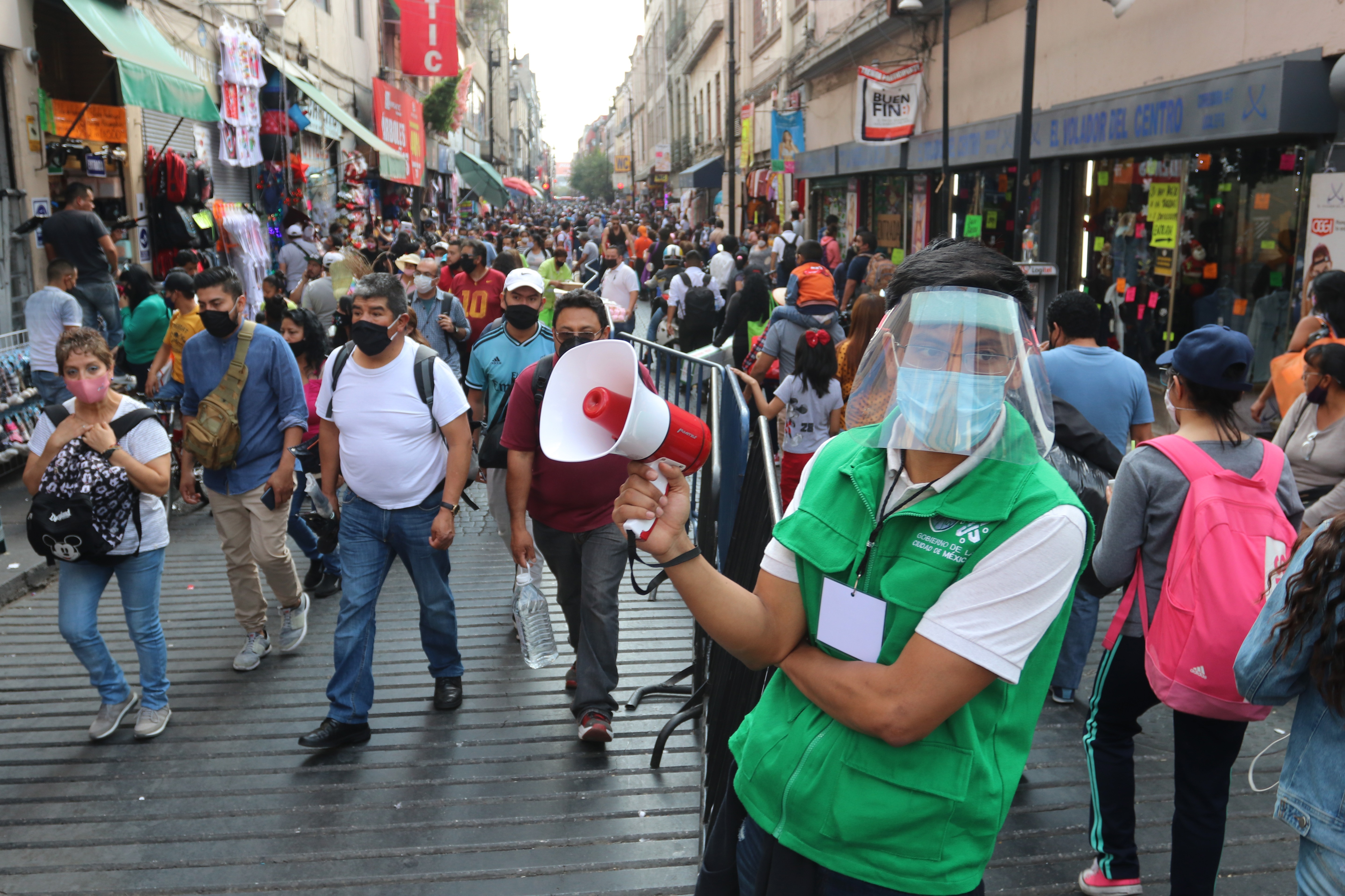 Un trabajador de la Gobernación de la Ciudad de México realiza una campaña para promover el distanciamiento social en una concurrida calle comercial, en el centro histórico de Ciudad de México (México). EFE/ José Pazos
