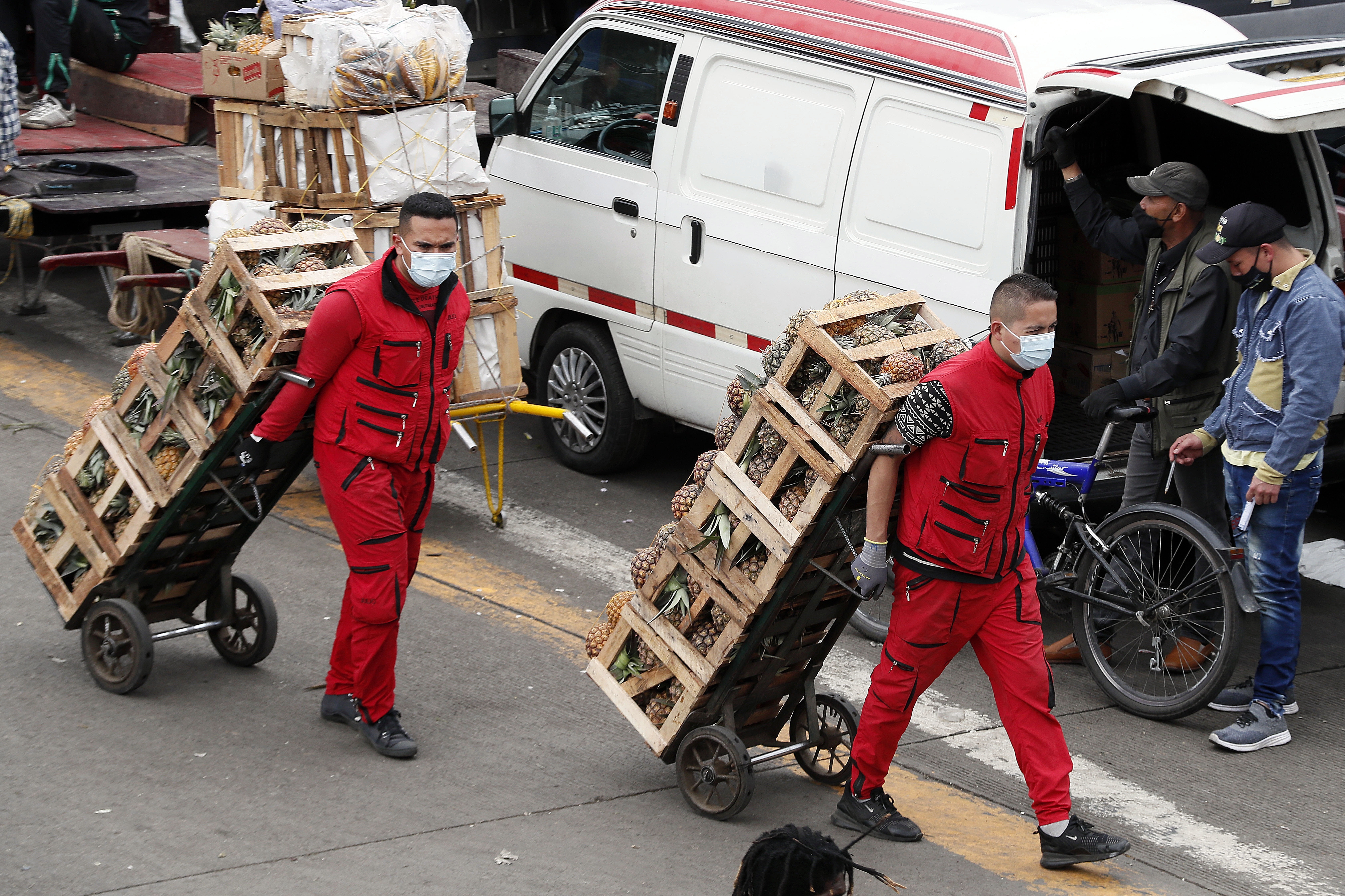 Trabajadores de la plaza de mercado Corabastos usan mascarillas para protegerse de la Covid-19, mientras empacan y trasladan alimentos en Bogotá (Colombia). EFE / Carlos Ortega/Archivo
