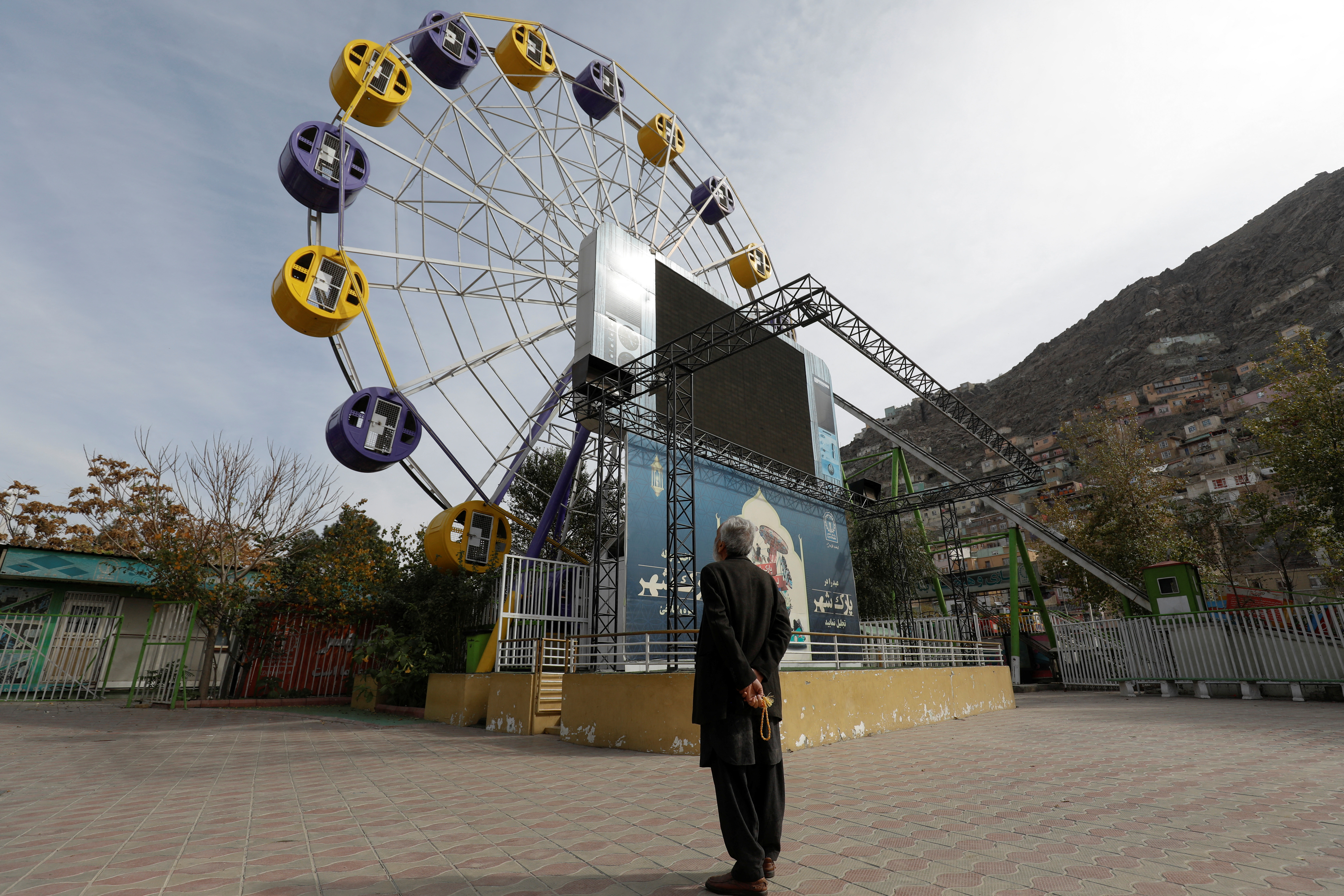 Un hombre afgano se encuentra en un parque de diversiones en Kabul, Afganistán después de que se la haya prohibido a las mujeres la entrada. 
REUTERS/Ali Khara