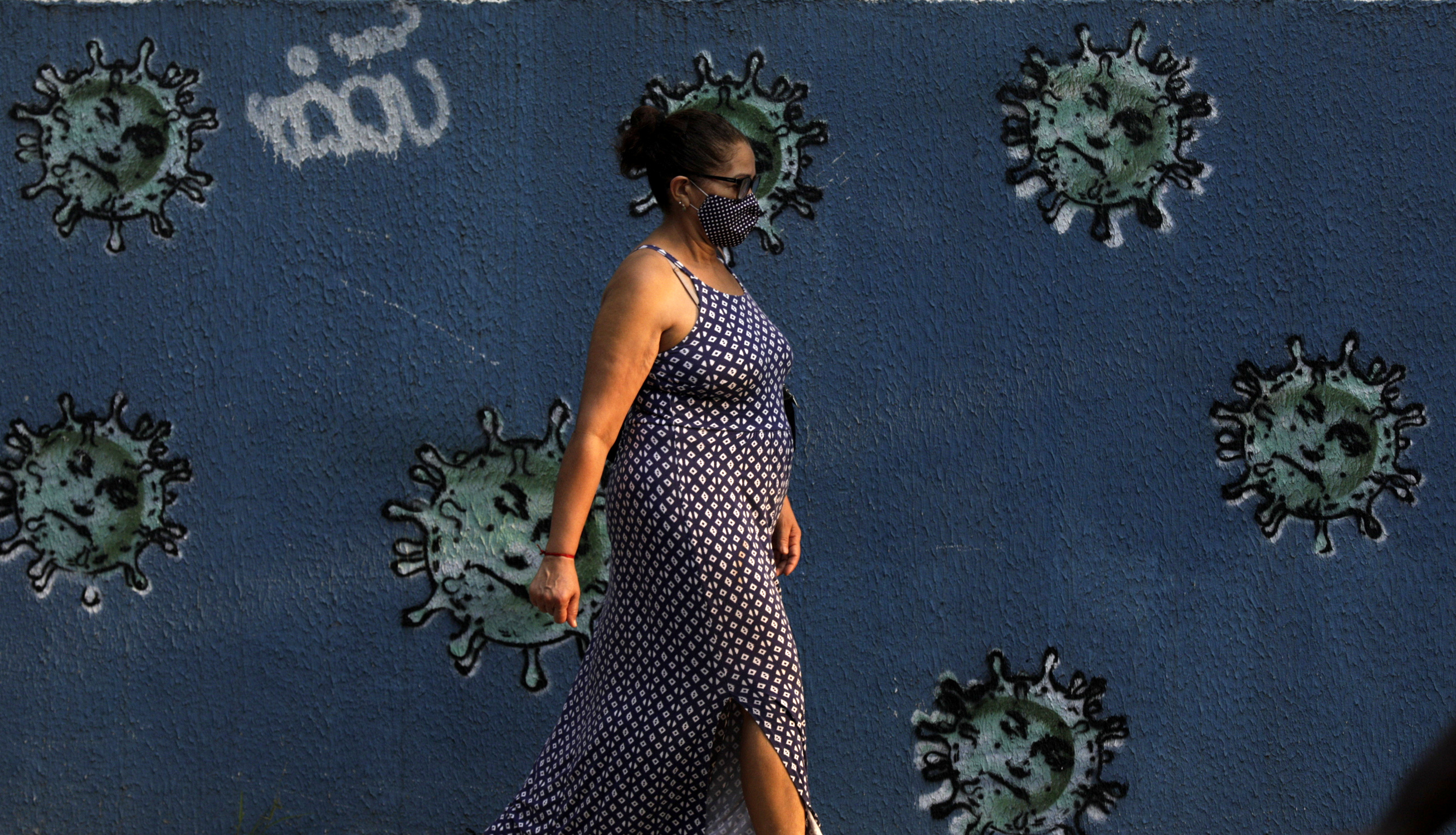 A woman walks next to graffiti depicting viruses with the face of Brazil's President Jair Bolsonaro, amid the coronavirus disease (COVID-19) outbreak, in Rio de Janeiro, Brazil, October 7, 2020. REUTERS/Ricardo Moraes
