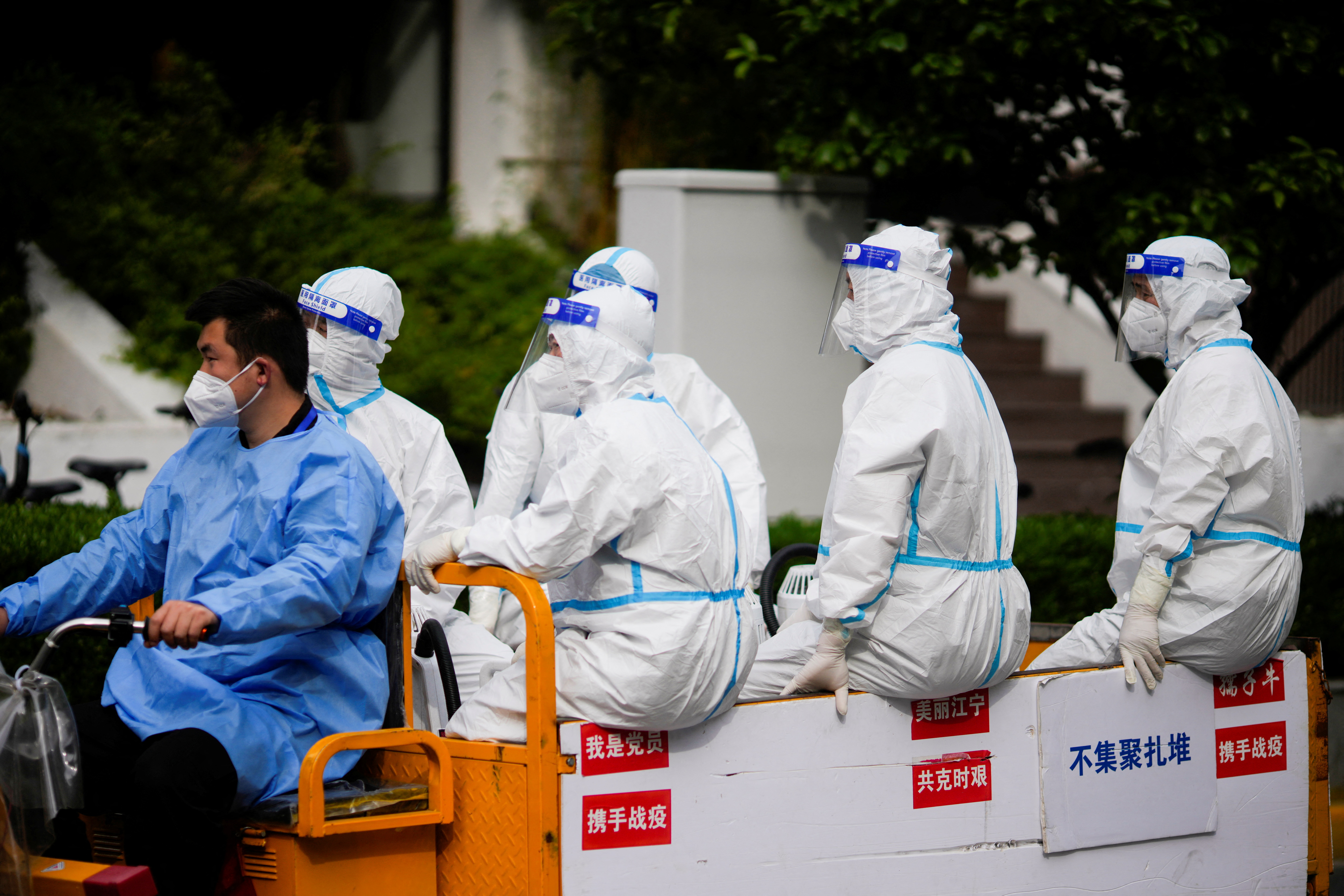 Trabajadores con trajes protectores montan un triciclo eléctrico en una calle durante el cierre en Shanghái, China, el 1 de mayo de 2022. (REUTERS/Aly Song)