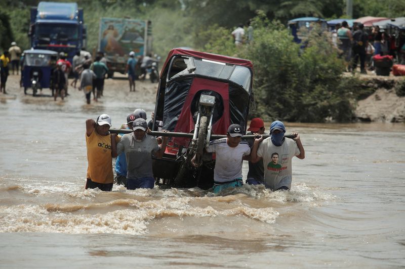 Residentes transportan un mototaxi a través de una zona inundada por efecto ciclón Yaku, en Piura, Perú, el 11 de marzo de 2023. REUTERS/Sebastian Castañeda