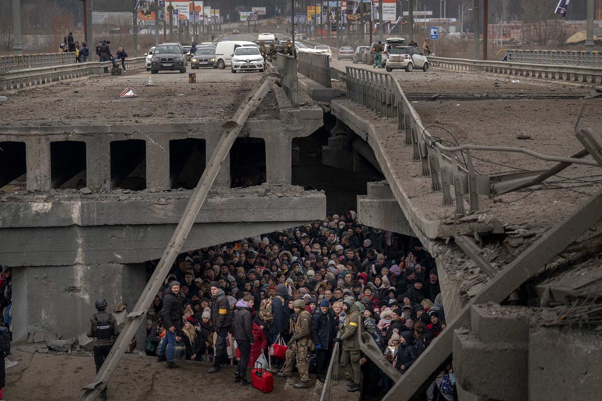 Civiles ucranianos reunidos bajo un puente destruido mientras intentan huir cruzando el Rio Irpin, en las afueras de Kiev.