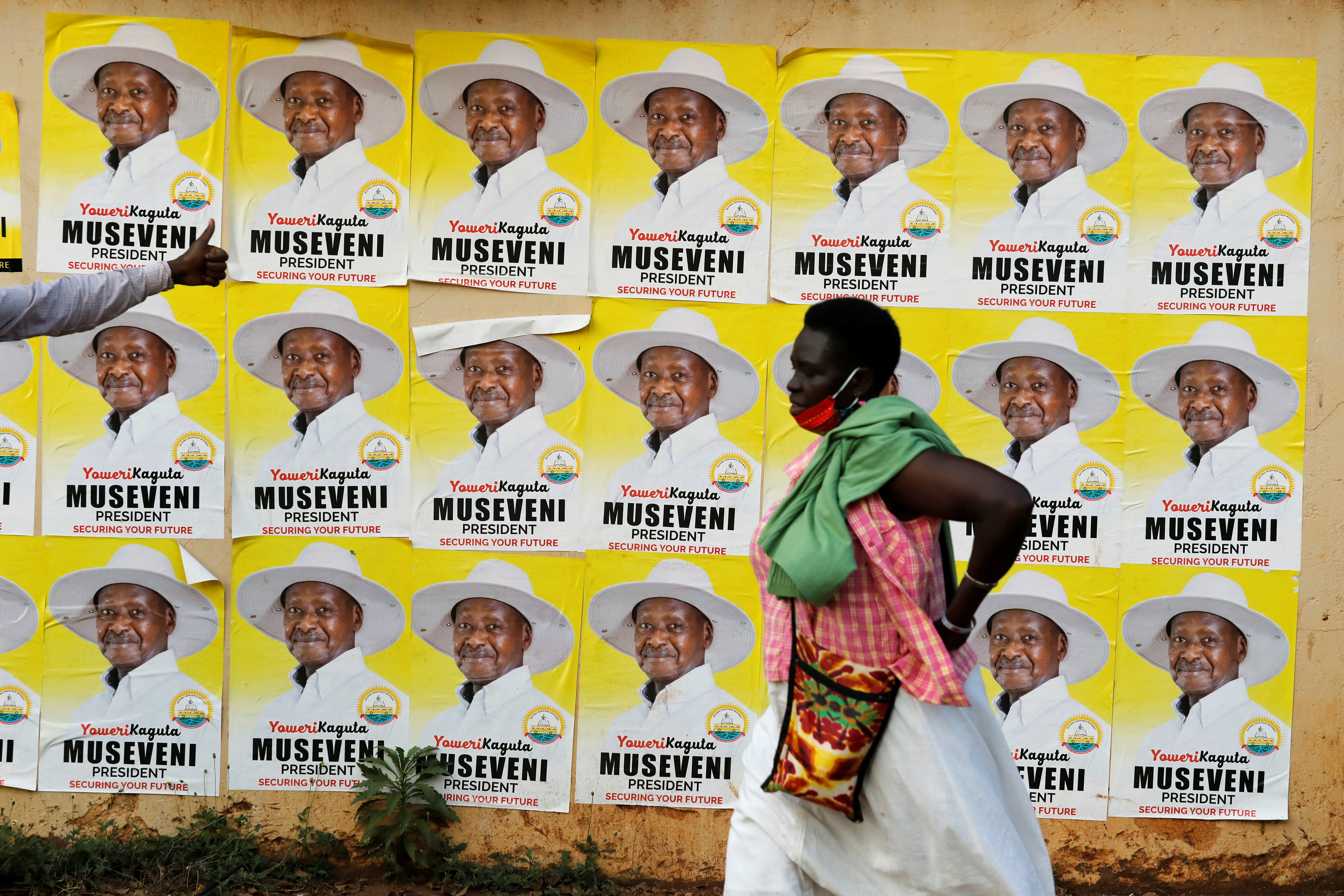 Una mujer camina junto a los carteles electorales del presidente de Uganda, Yoweri Museveni, en una calle de Kampala, Uganda, el 12 de enero de 2021 (REUTERS/Baz Ratner)