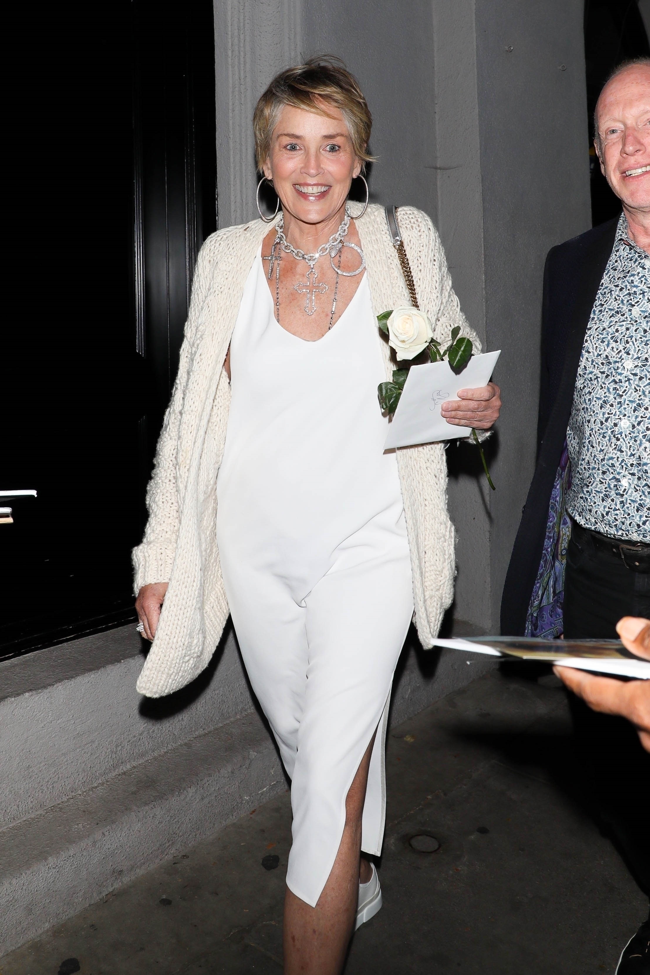 Una noche divertida. Sharon Stone fue a comer a un exclusivo restaurante de Los Ángeles y lució un look off: white de vestido, sweater y zapatillas de cuero. y una carta en su mano
