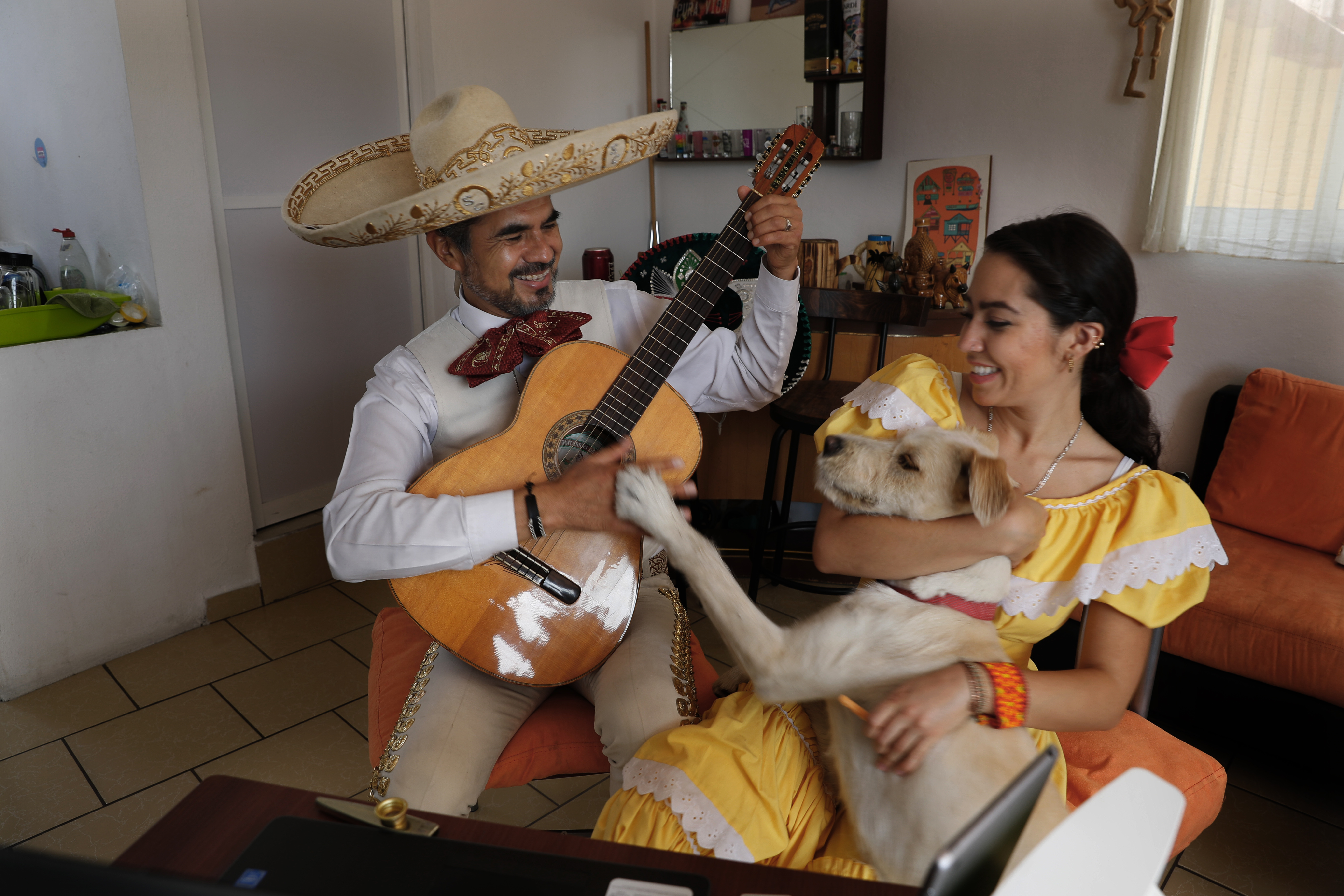 El Mariachi Duo Villa Maria, Sergio Carpio, a la izquierda, y Melissa Villar, acompañados por su perro Güiro, se presentan a través de Internet para un cliente durante el día de las madres. (Foto: AP/Marco Ugarte)